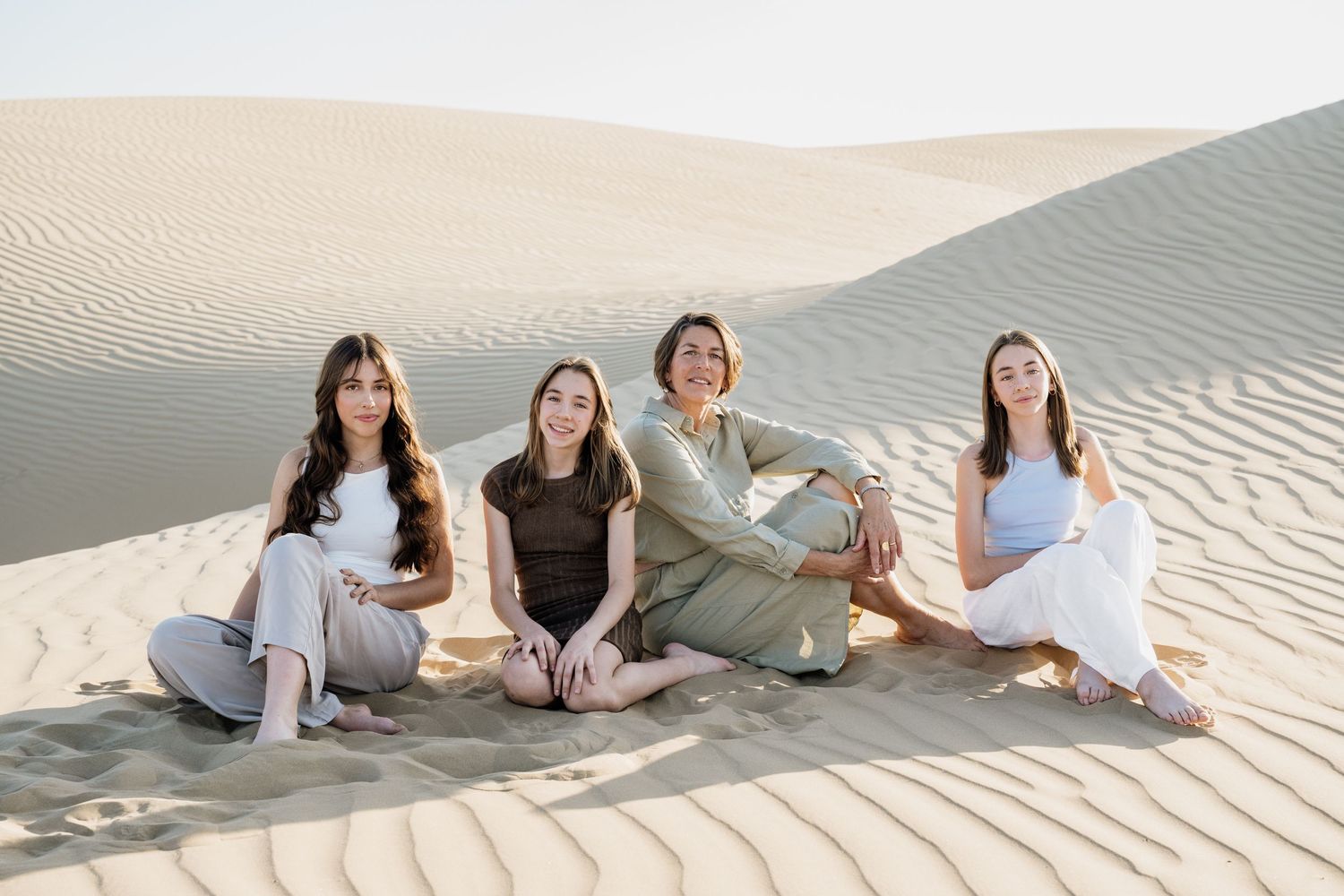 Group relaxing together on sandy slopes during desert photoshoot.