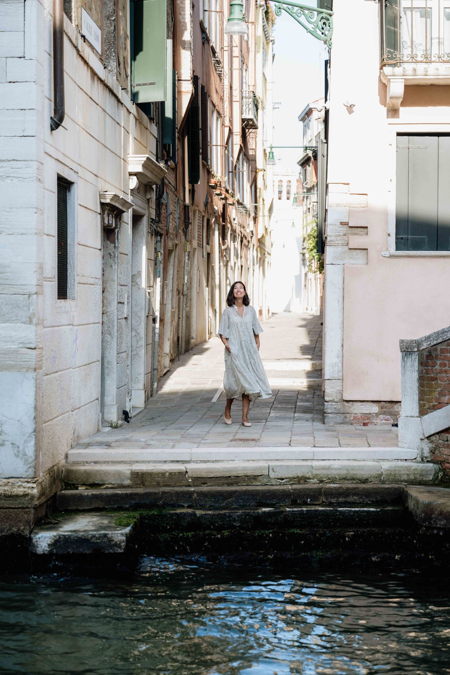 Scenic view of narrow Venice canal with white buildings and stone walkways.