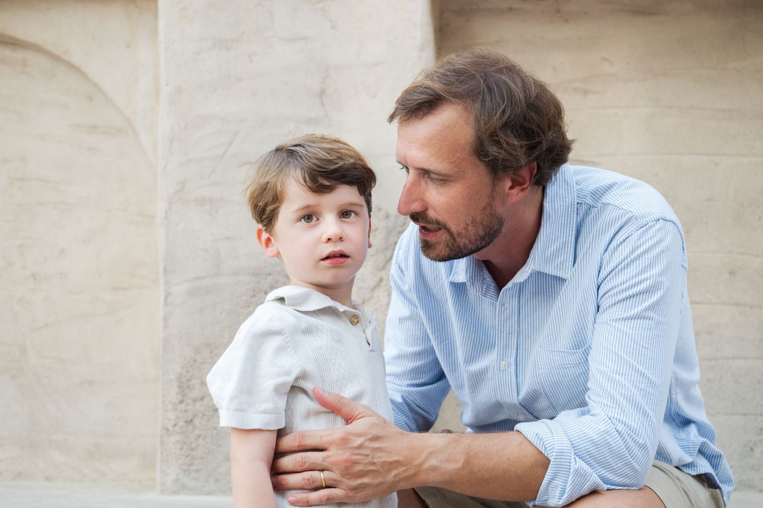 Emotional moment between parent and child against beige wall background.