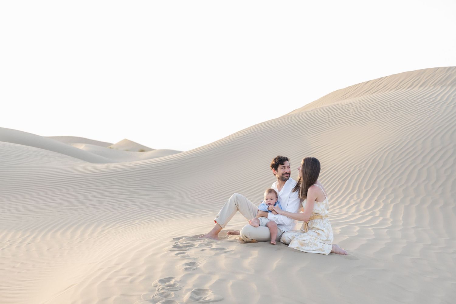 Intimate family photoshoot on rolling sand dunes during golden hour.