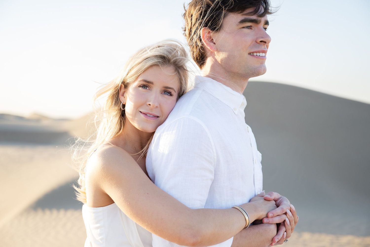 Romantic couple embracing on beach during golden hour sunset photoshoot.