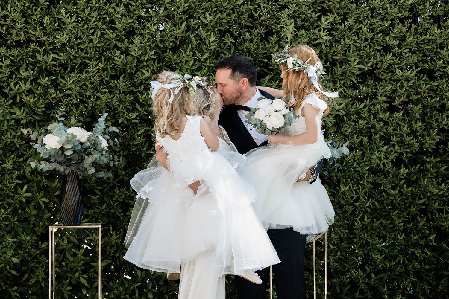 Wedding party members celebrating with flower girl in white tulle dress.