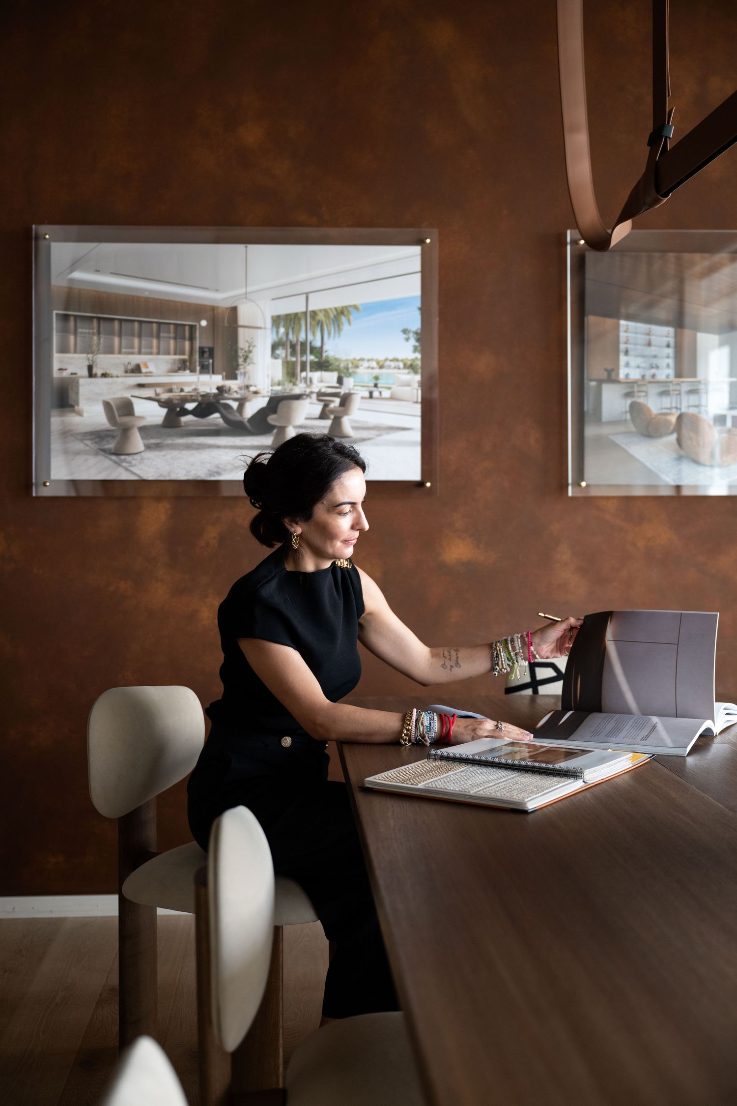 Professional working at a modern desk with laptop and coffee in an office with brown walls and natural lighting.