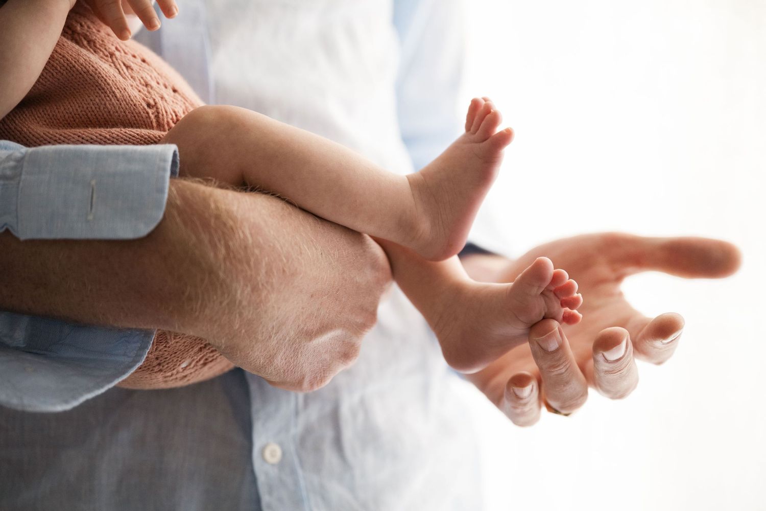 Newborn detail shot of father holding a baby and touching the tiny toes
