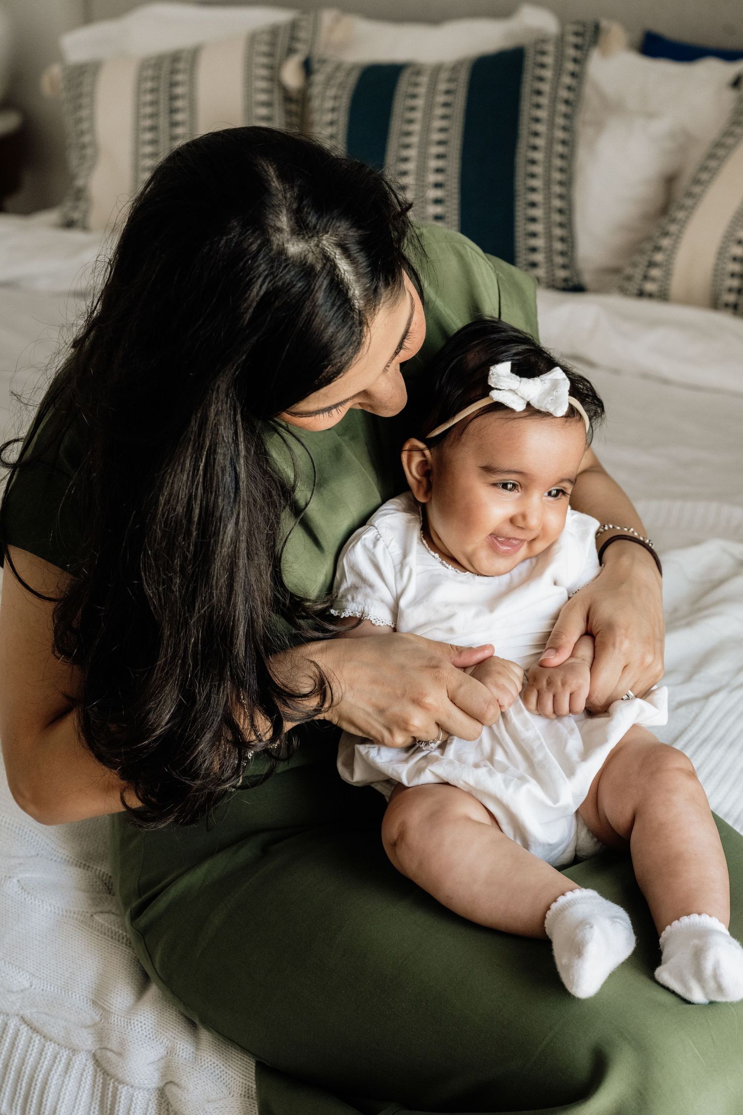 Candid lifestyle photos showing tender moments between parent and infant on bed.
