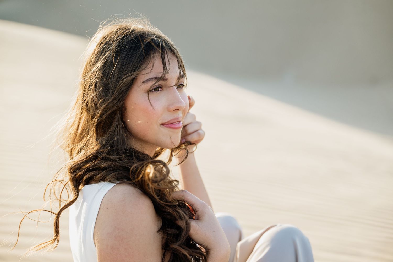 Close-up portrait shots on sand dunes with soft natural lighting.