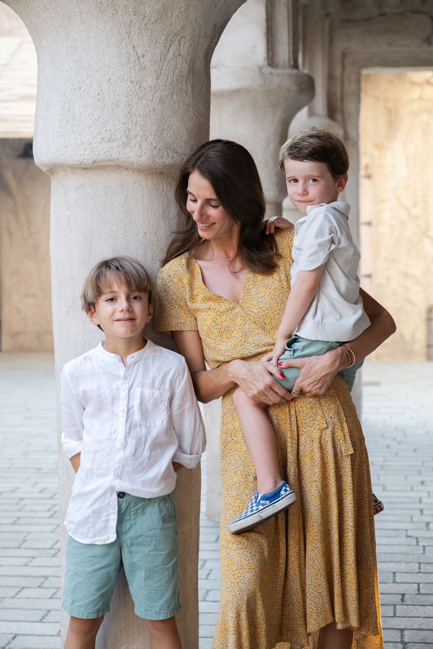Casual family portraits taken in a stone corridor with natural lighting.