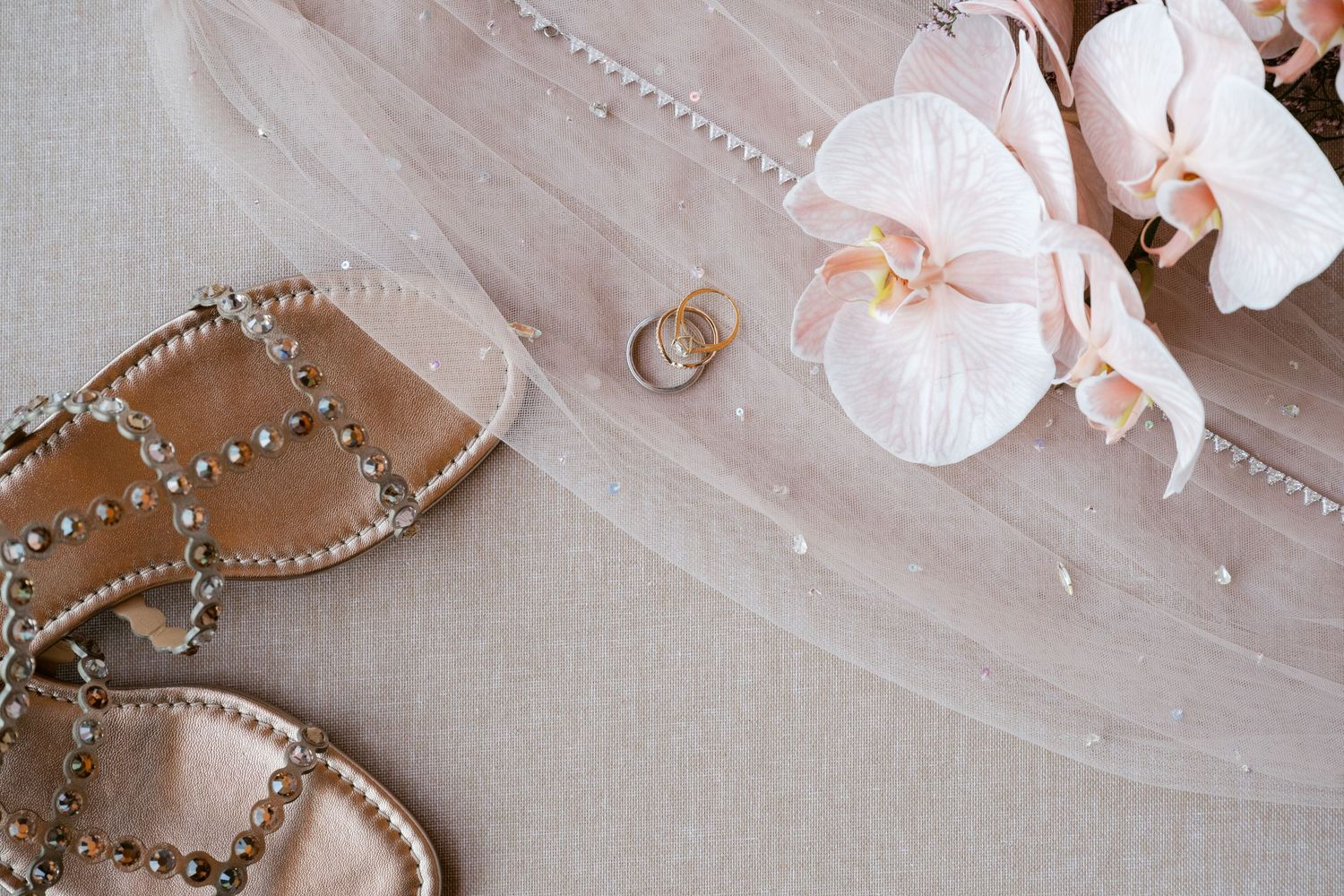 Pearl beaded accessories and floral details arranged on soft pink fabric.