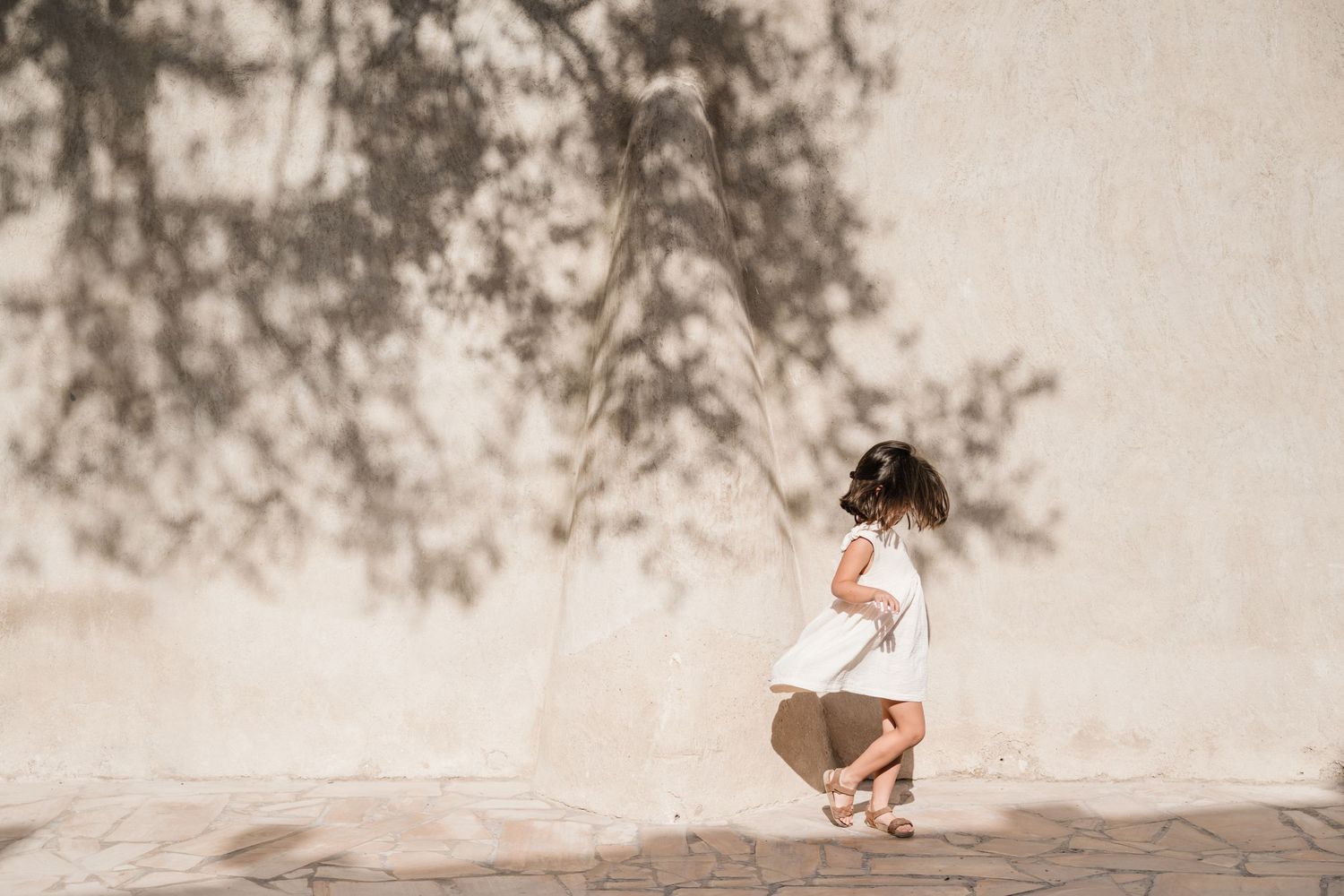 Artistic photo of a twirling girl in Old Dubai, with a beautiful shadow from a tree