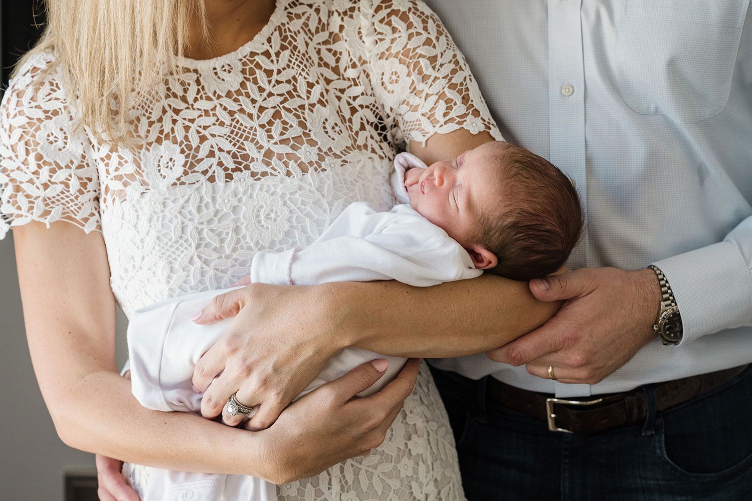 Photo with dramatic light showing a newborn baby being held in parents' arms