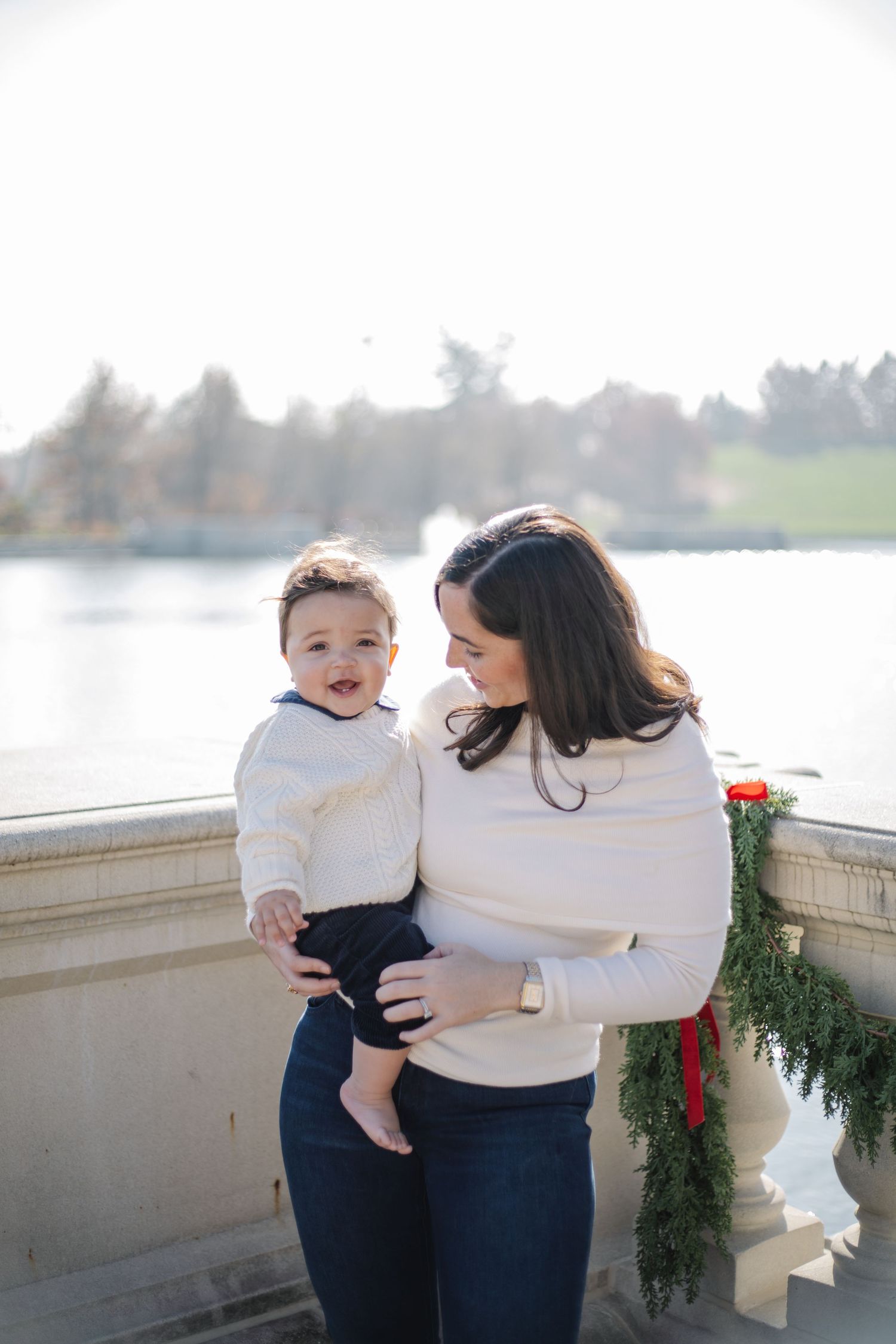 Candid family photos captured on a stone balcony decorated with holiday greenery.