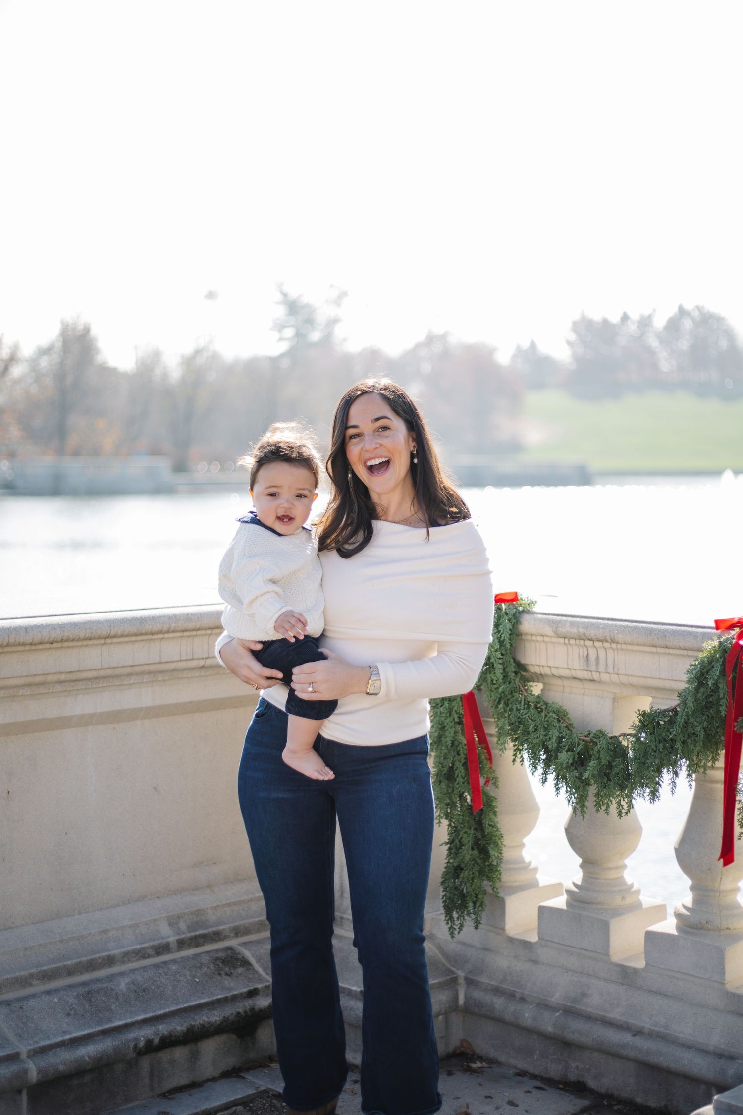 Candid outdoor family photo with holiday decorations and lake in background.