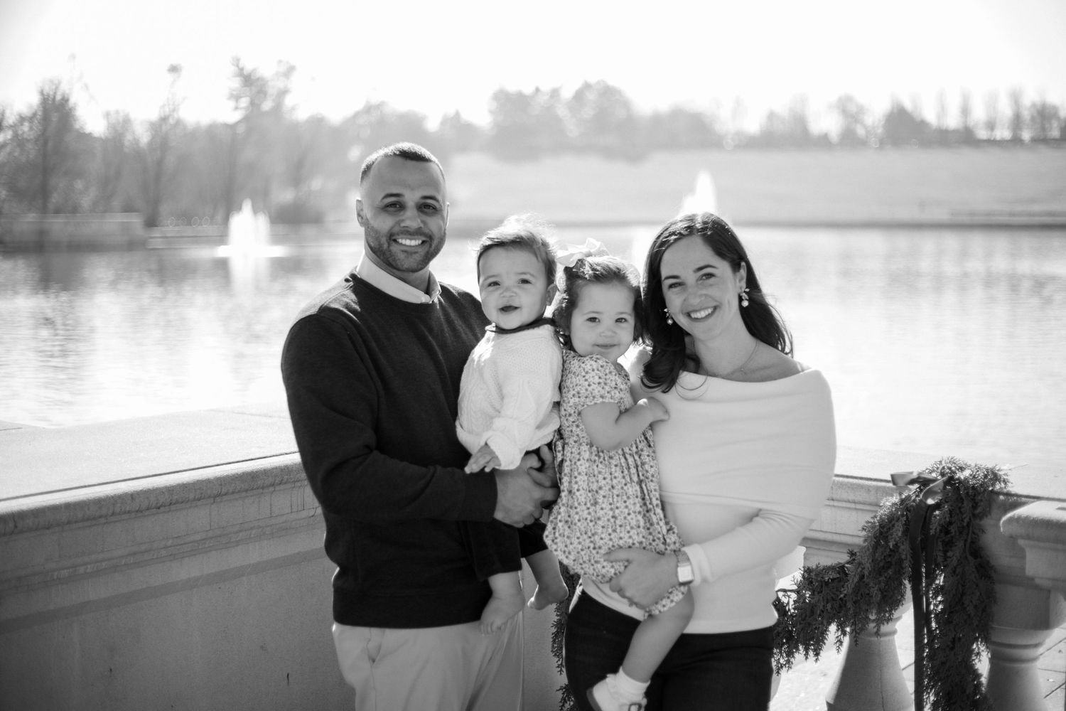 Black and white family portrait by lake with holiday decorations.