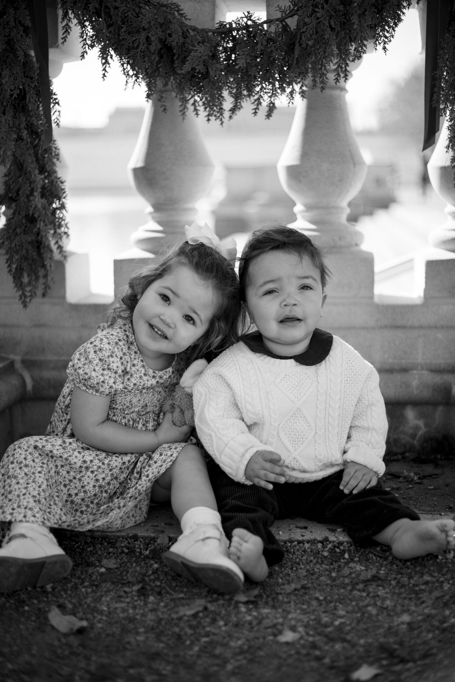 Black and white photos of children sitting together under decorative outdoor railings.