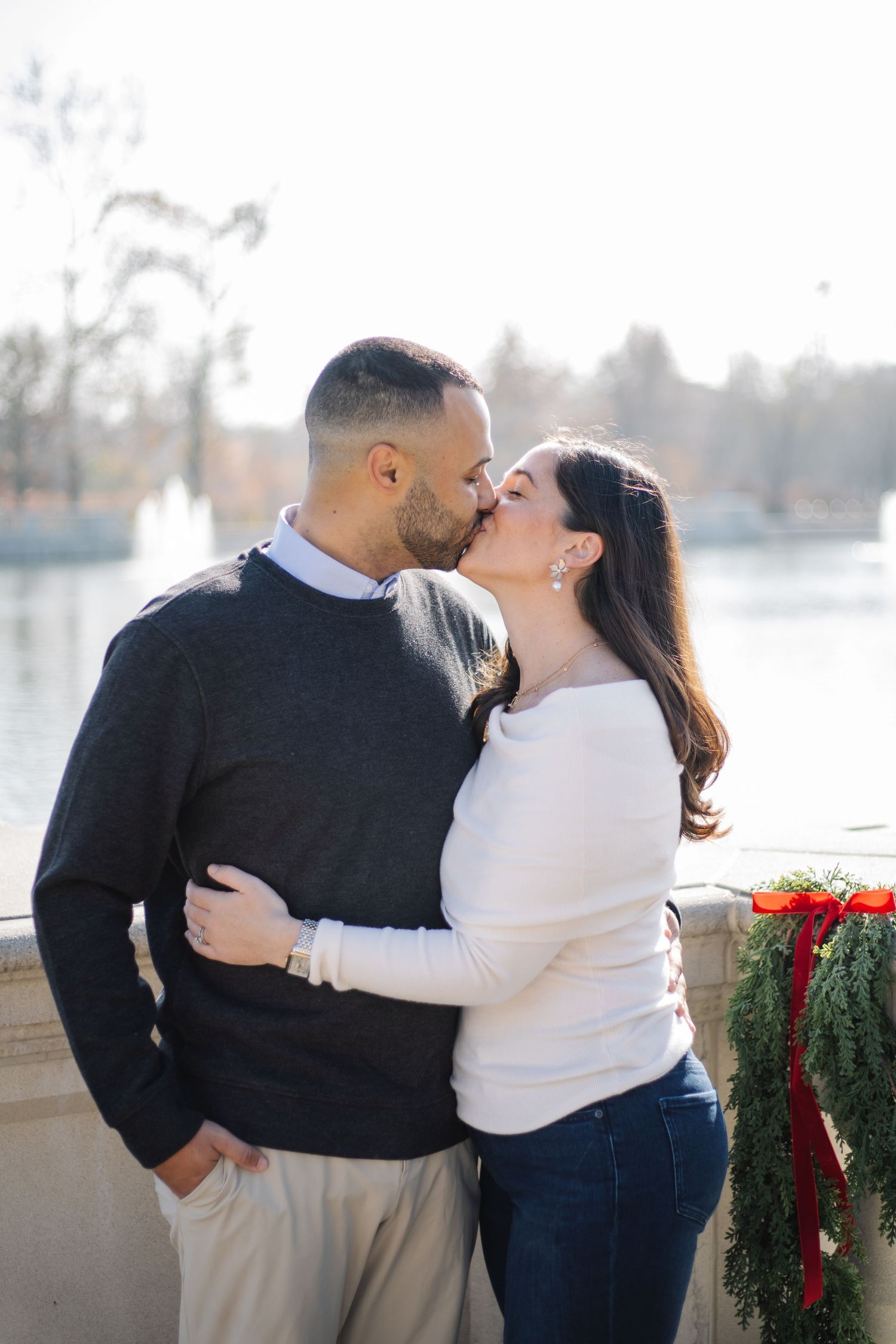 A romantic moment captured between a couple on a balcony with winter decorations.