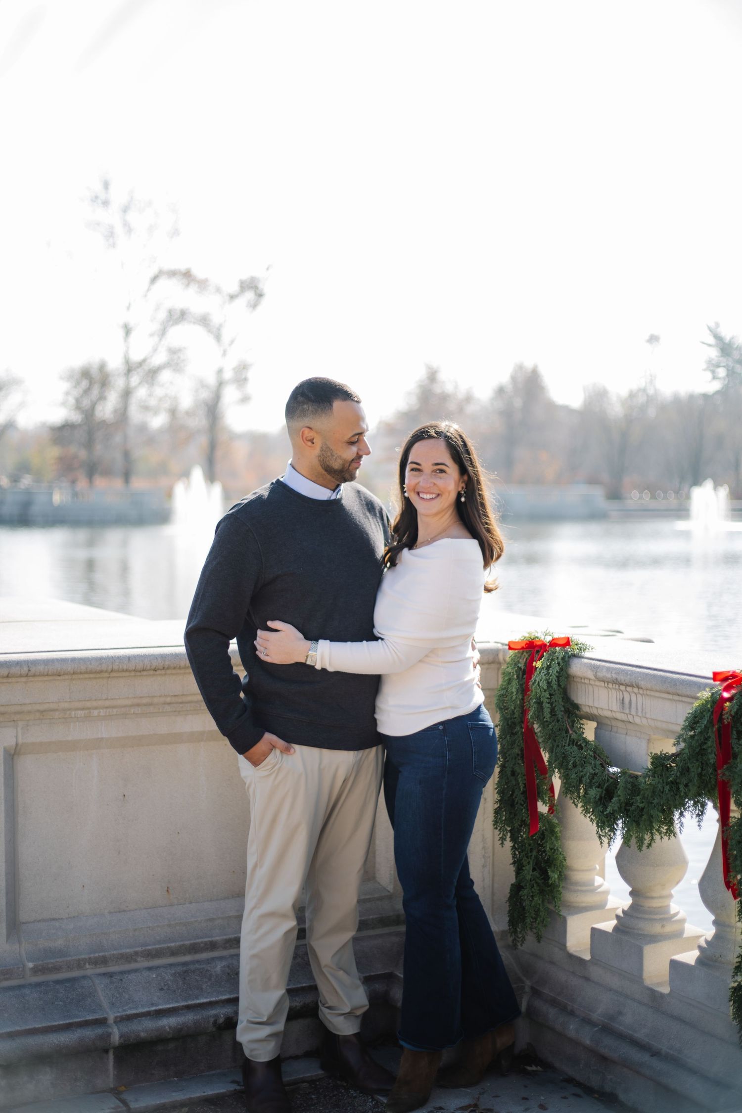 Romantic couple portrait by stone balustrade with evergreen holiday decorations.
