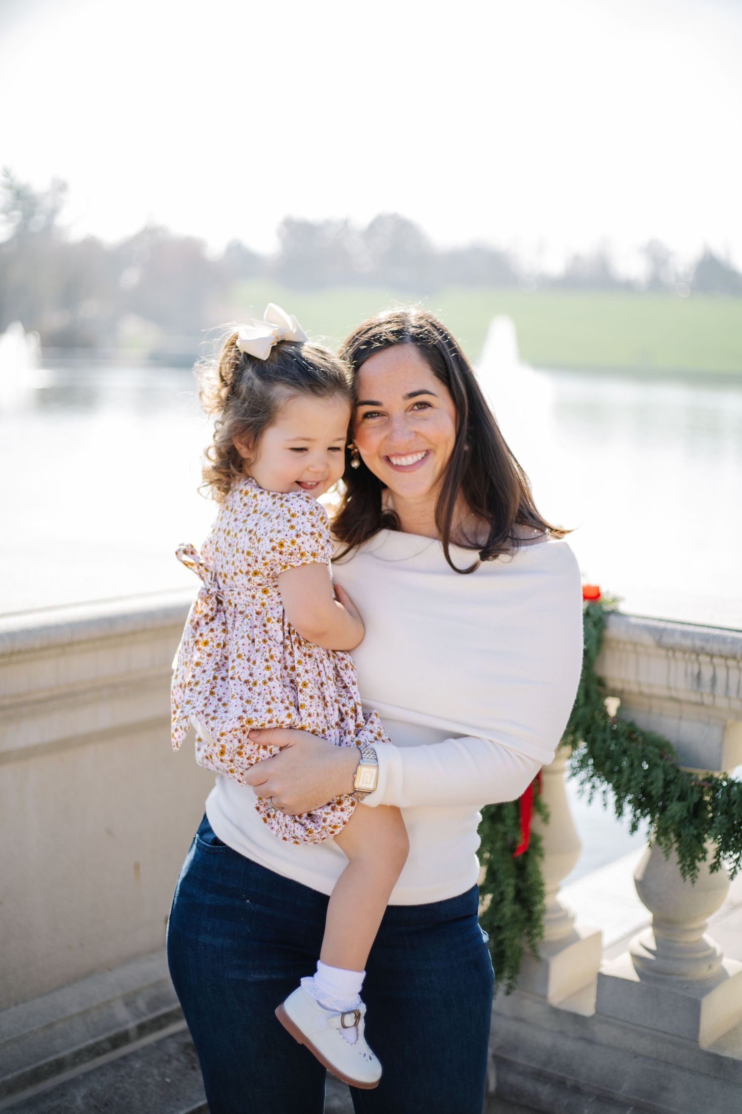 A heartwarming family moment captured outdoors near decorative stone columns with festive greenery.