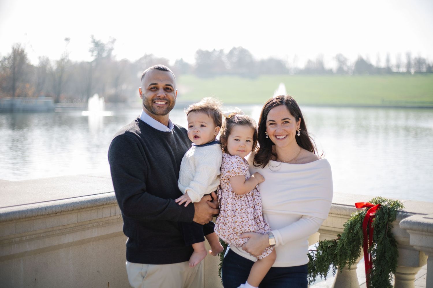 A family embraces while posing for holiday photos on an outdoor terrace with festive decorations.