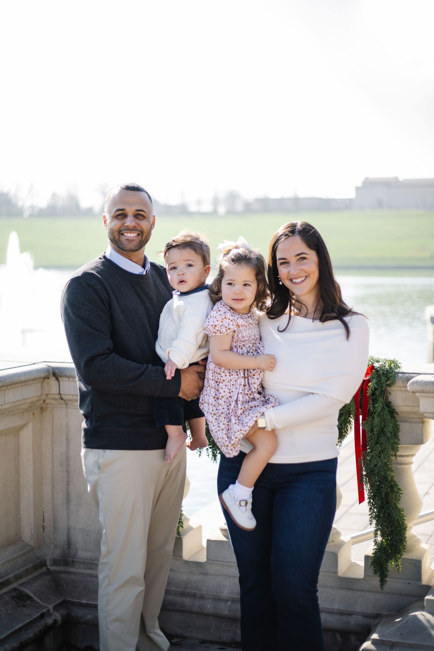 A family shares a tender moment together on a stone balcony overlooking a scenic landscape.