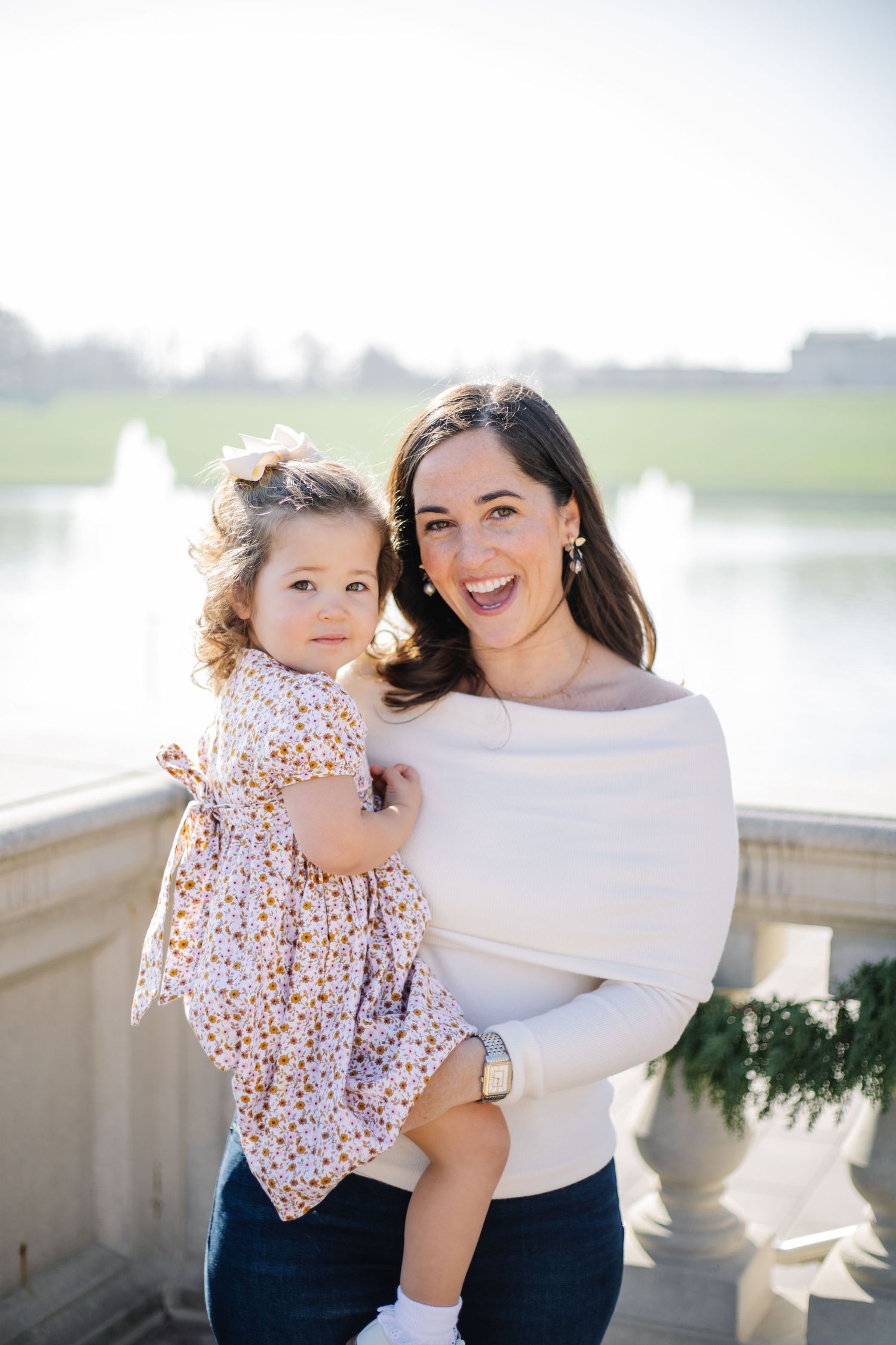 A parent and child share joyful moments together outdoors in matching white and navy outfits.
