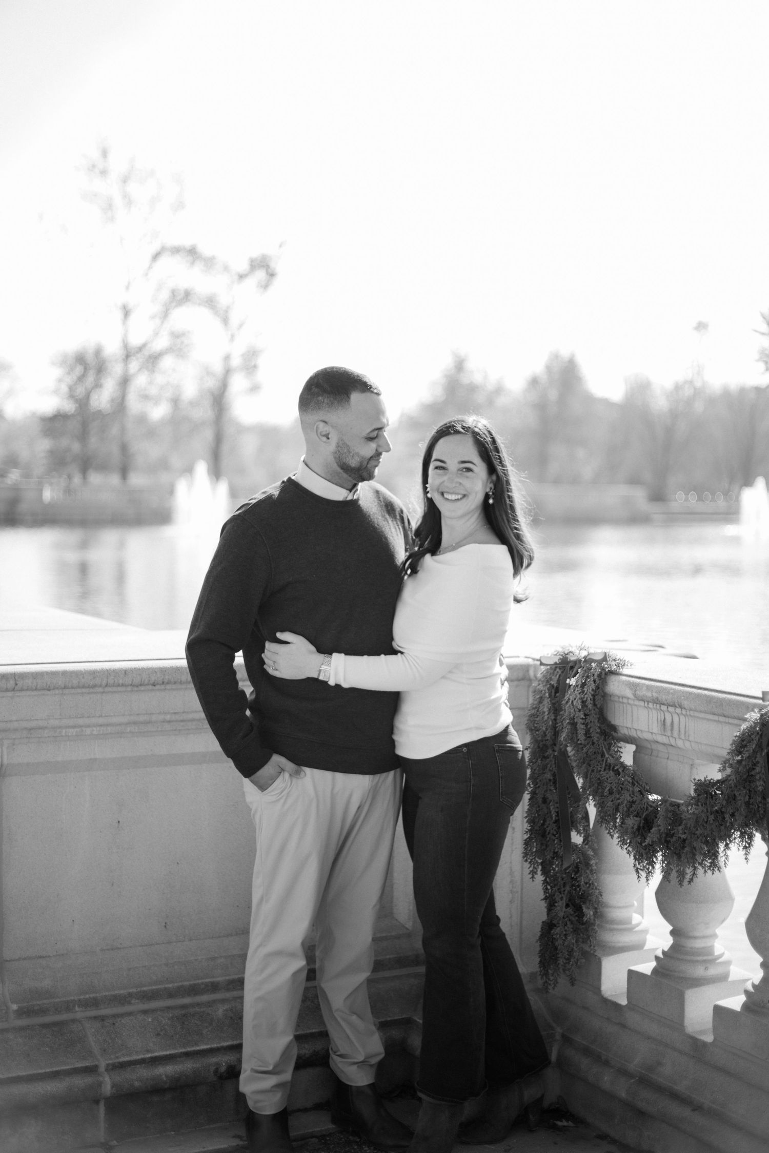 A couple shares a romantic moment on a balcony in black and white photography.