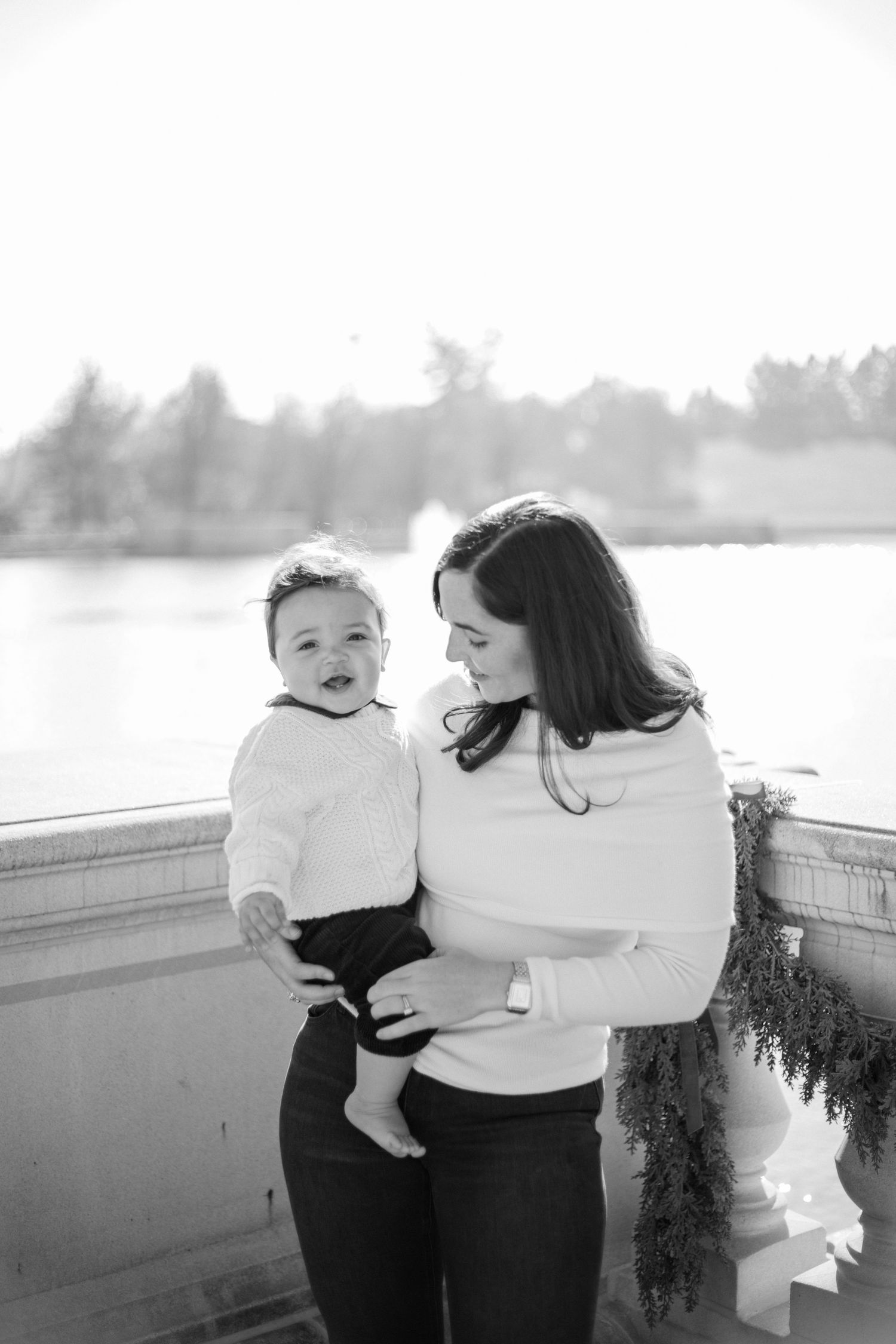 A black and white photo series showing tender moments between parent and child on a lakeside dock.