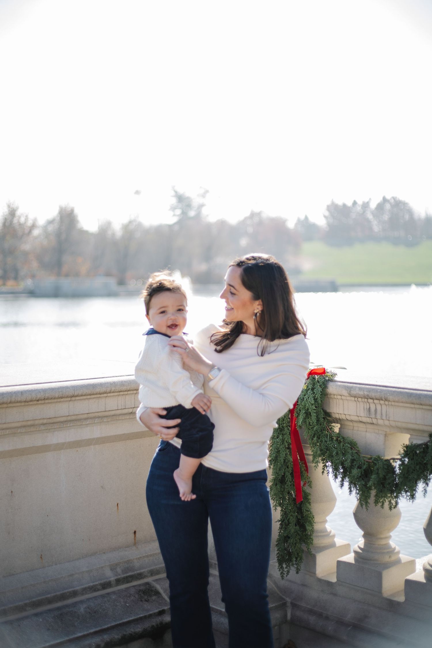 Family members share tender moments on a stone balcony decorated with holiday greenery.