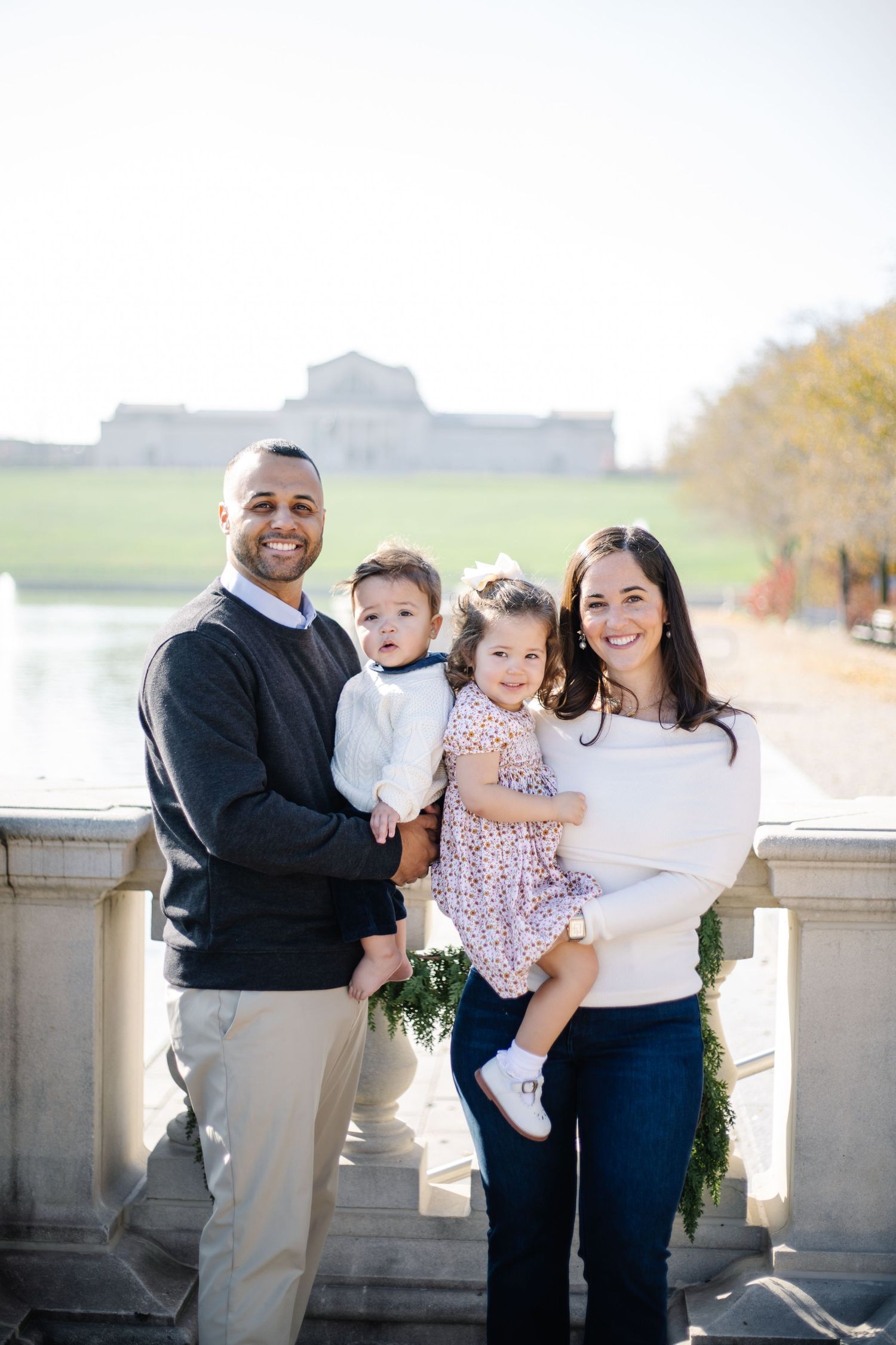 Family holiday photos captured on a stone balcony with evergreen garlands and water views.