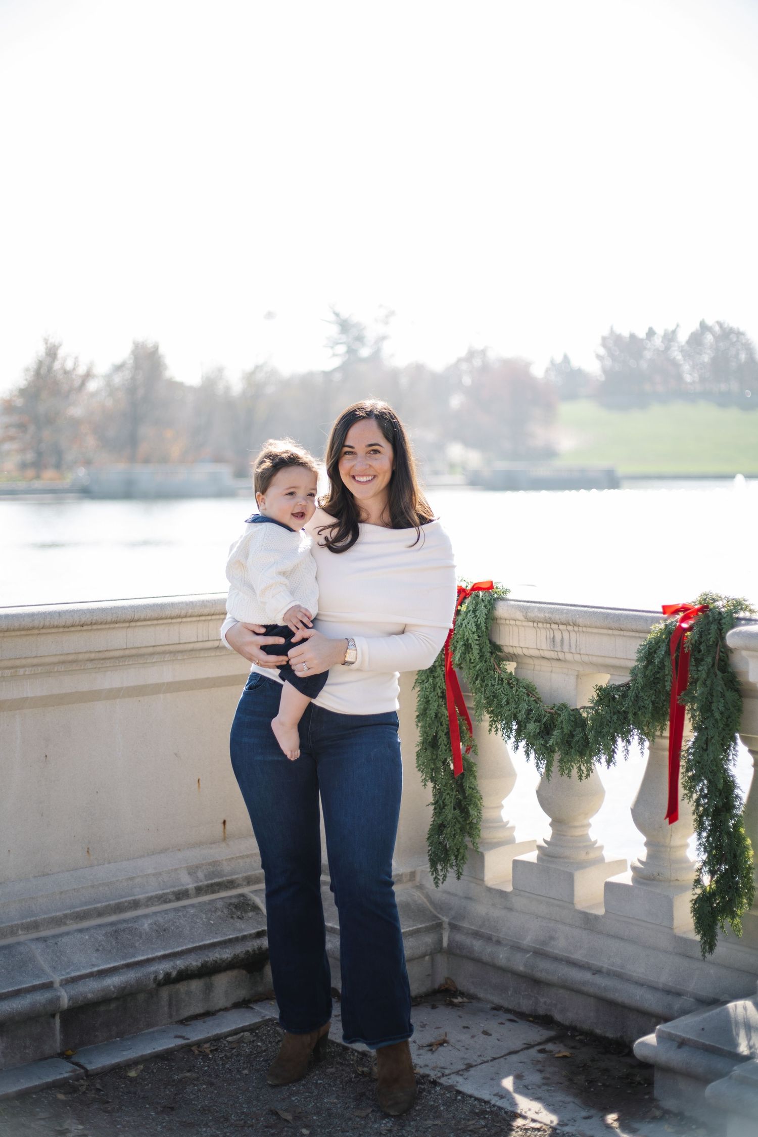 A family photoshoot on a stone terrace with evergreen garlands and water views.