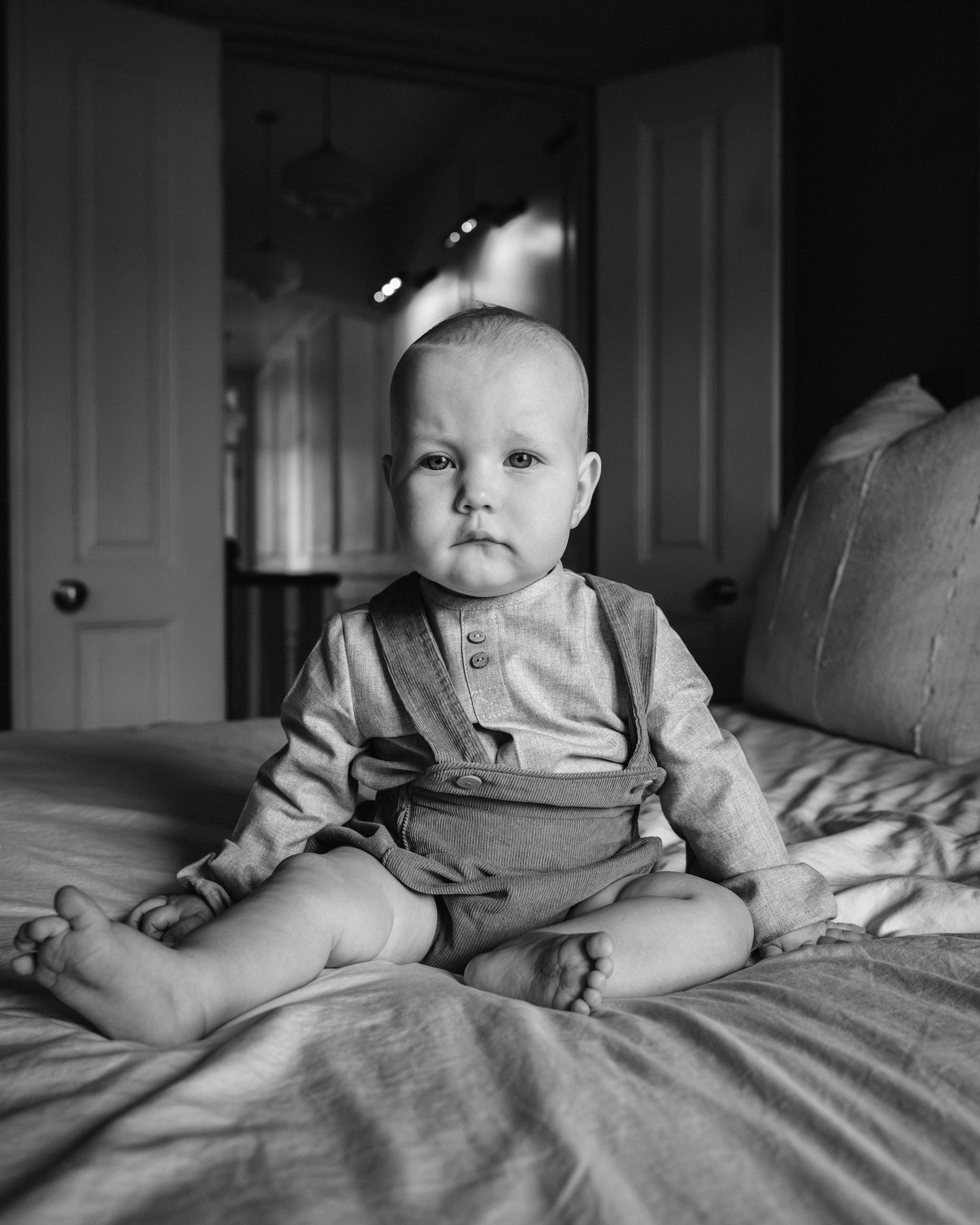 Sequential black and white shots of a baby sitting on bedding.