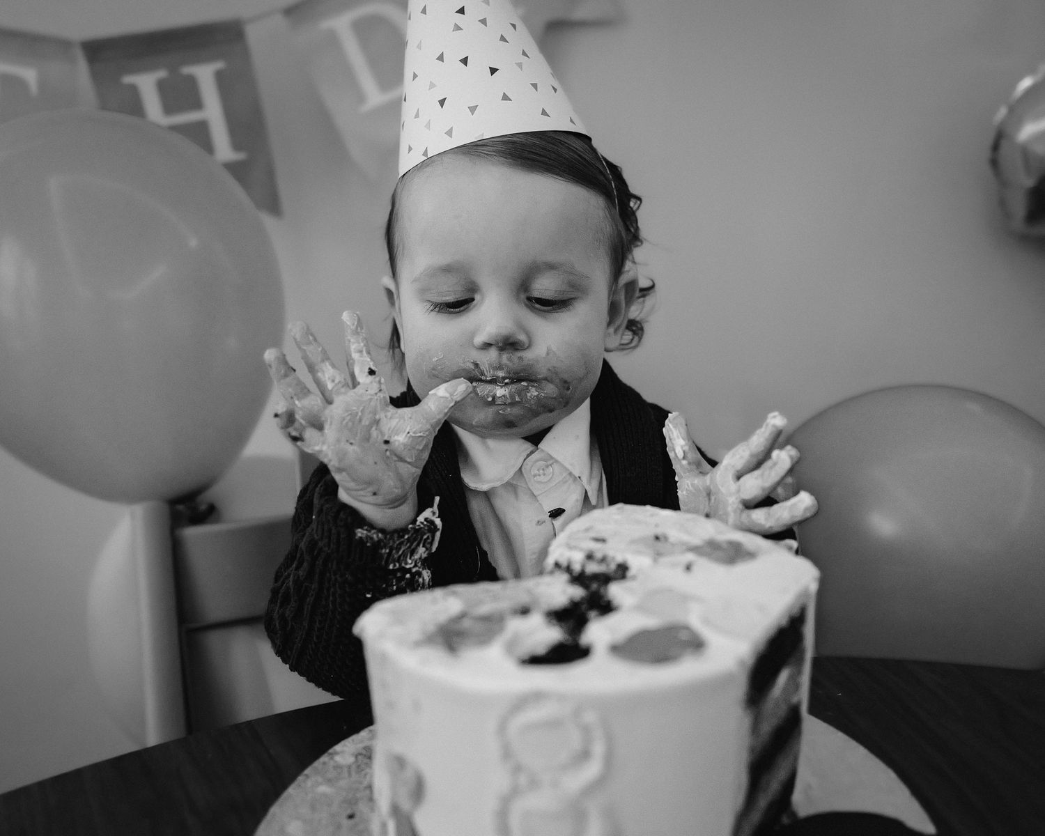 Child's birthday celebration with cake and party decor in black and white.