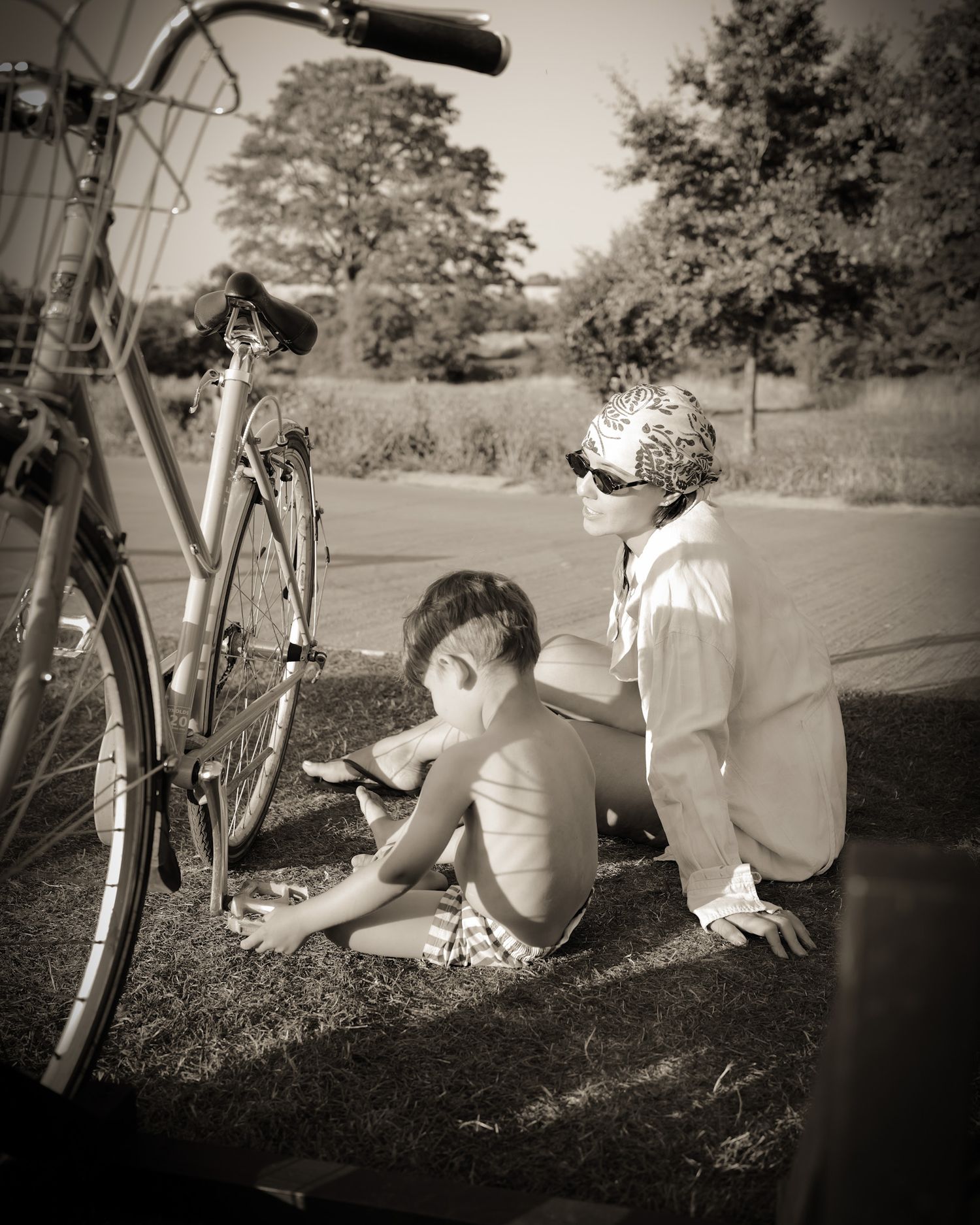 Vintage style panoramic sequence showing mother and child resting beside a bicycle outdoors.