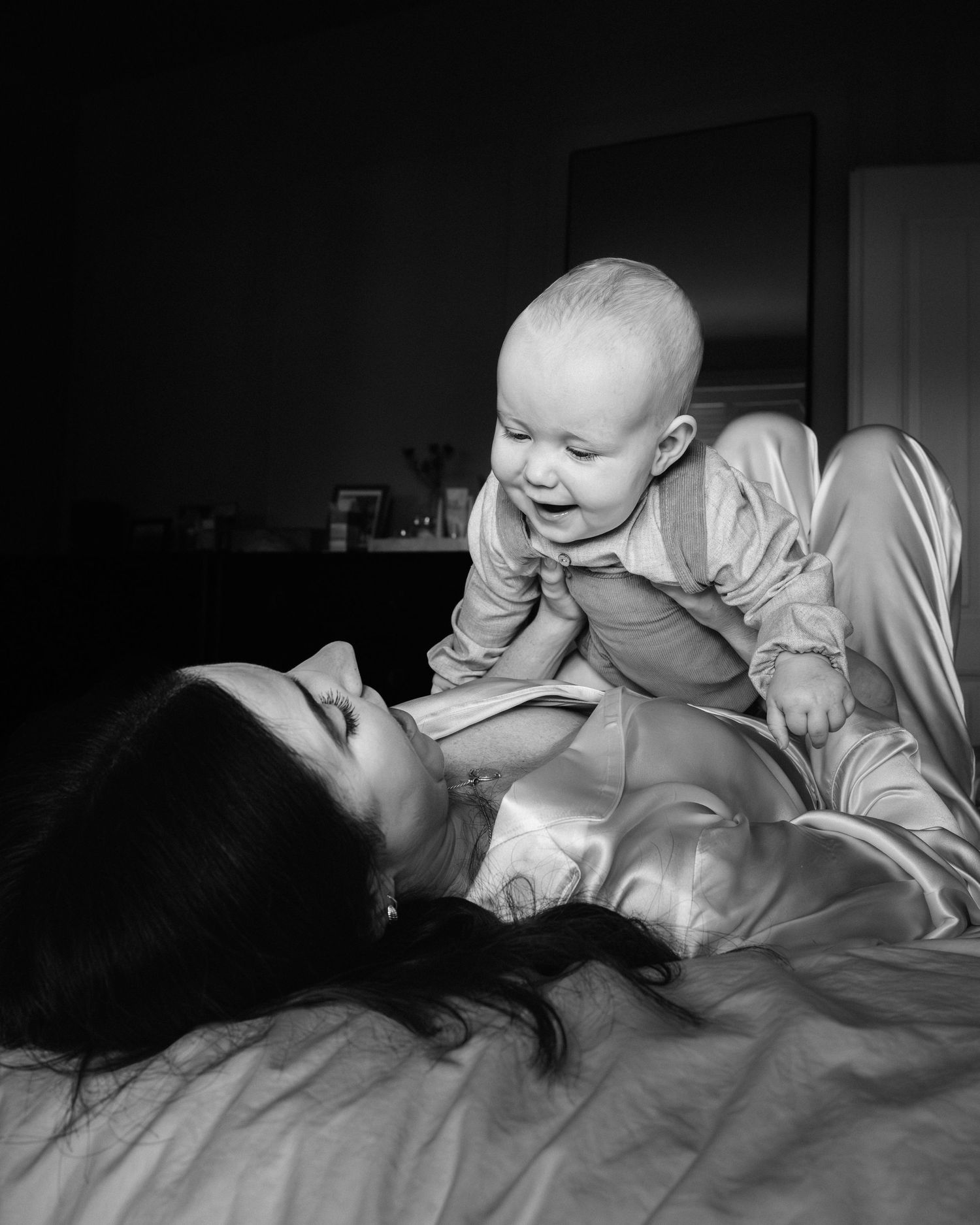 Black and white image of joyful interaction in bed with natural light.