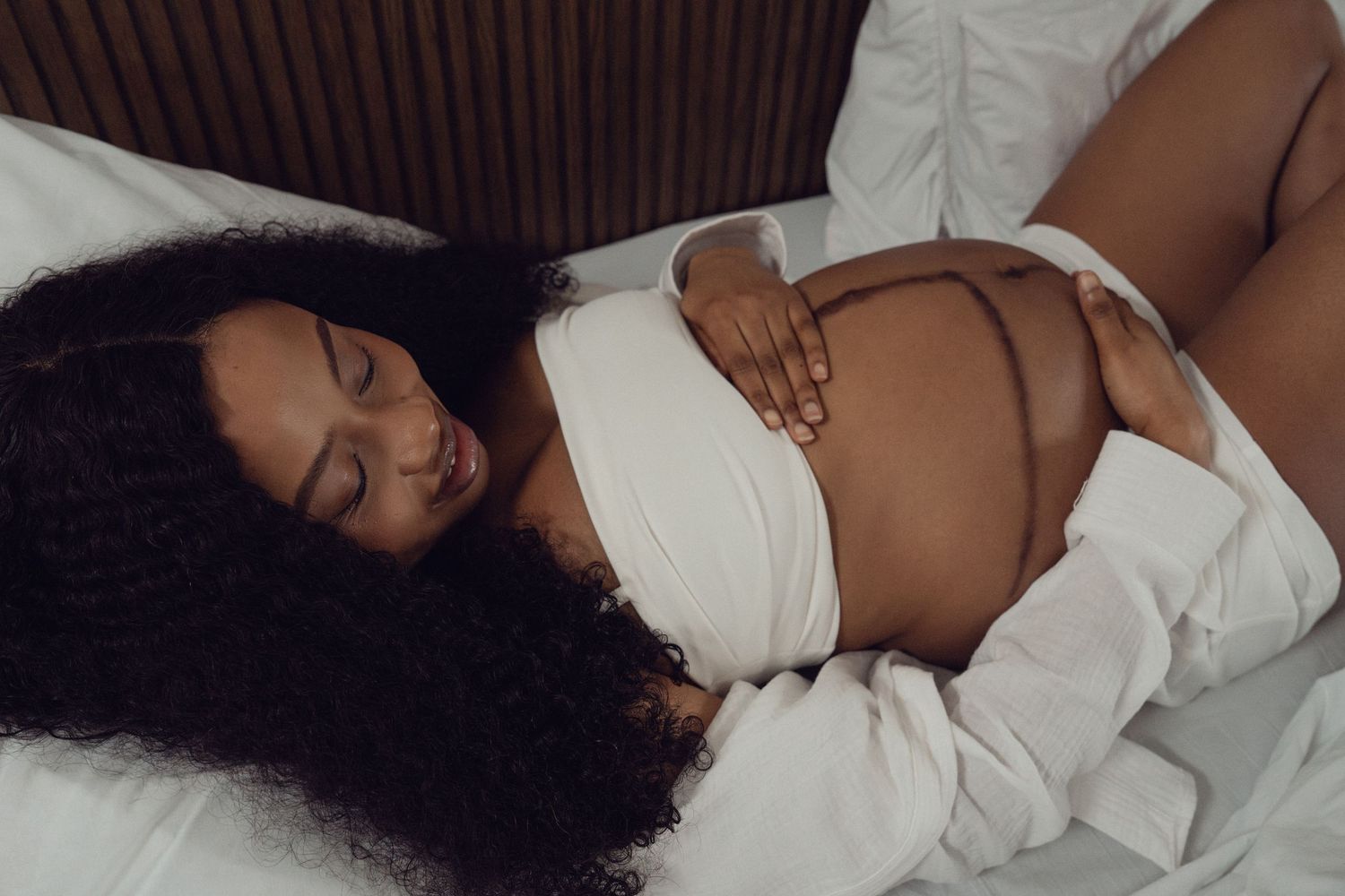 At-home maternity portrait, expectant mother cradling baby bump | London maternity photographer by Inga Franlund
