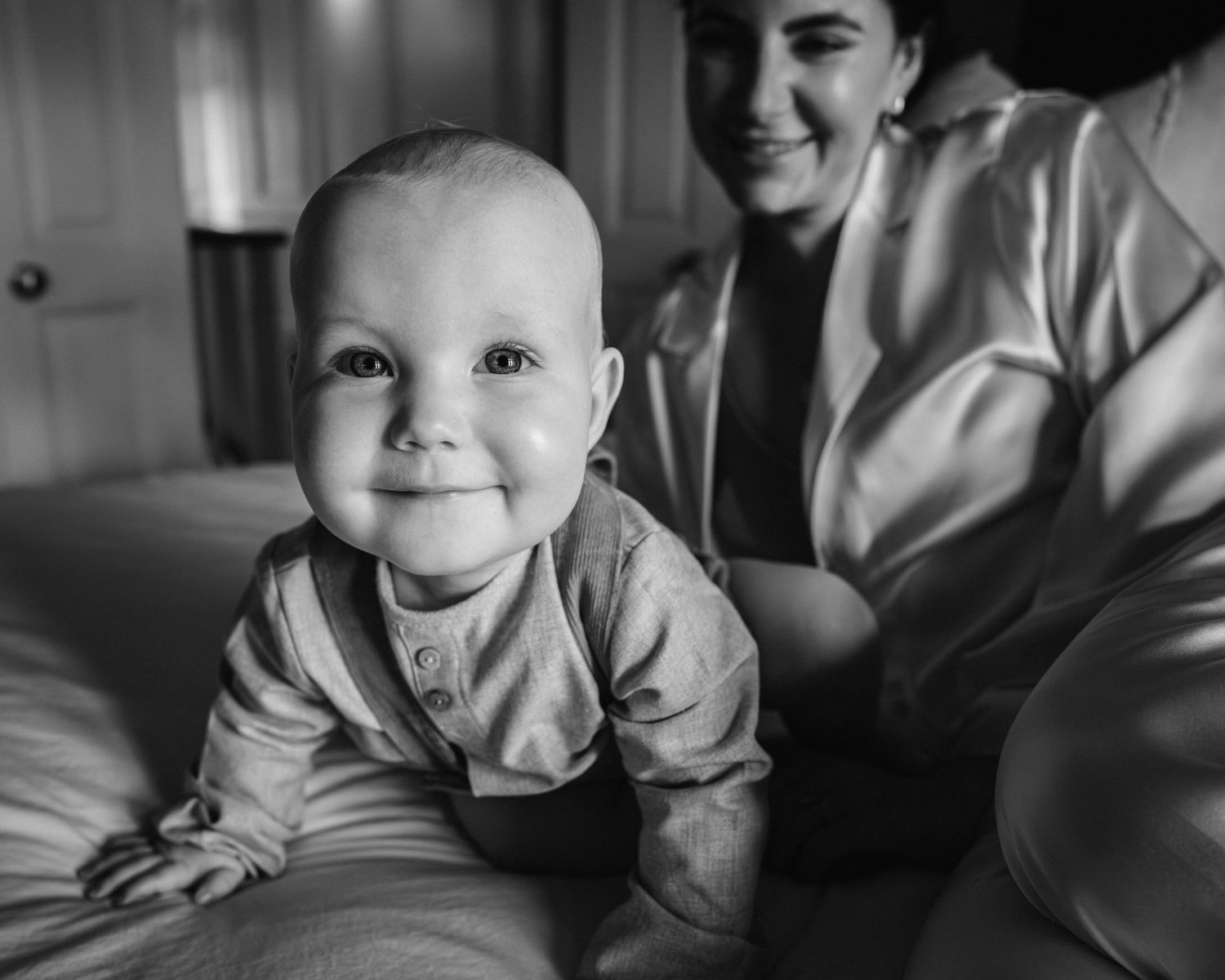 Black and white photo series of a baby in light colored clothing on furniture.