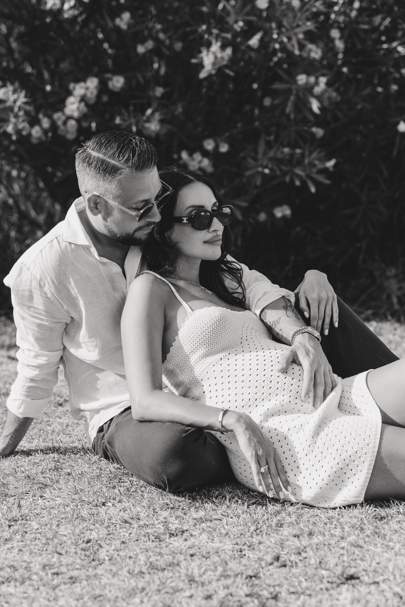 Black and white photo of a couple relaxing together outdoors on grass.