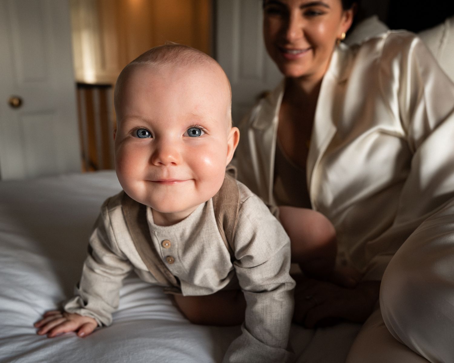 A series of candid lifestyle photos showing a baby in white clothing lying on a bed in natural light.