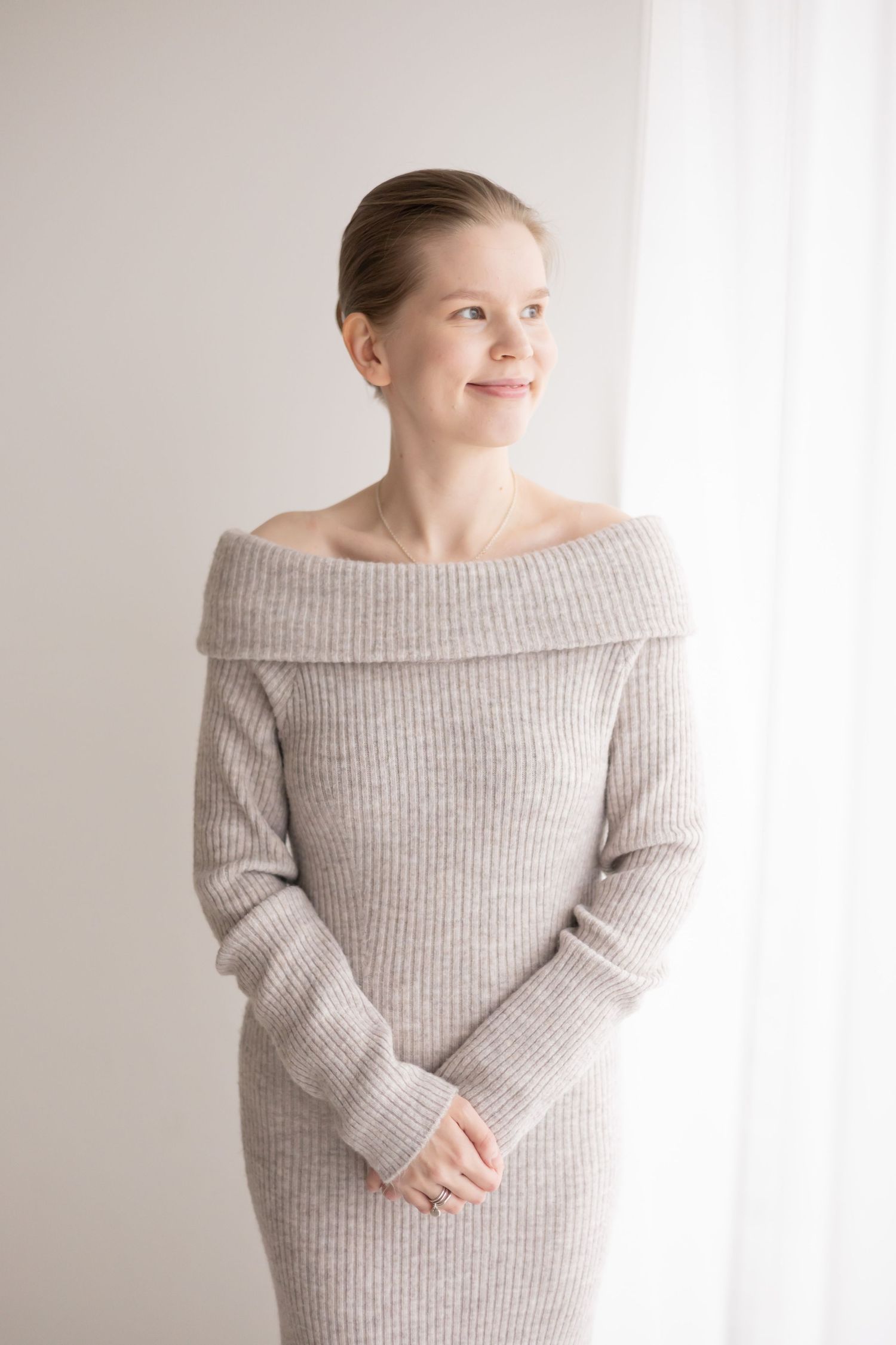 Minimalist studio portrait series of someone wearing a cozy off-shoulder gray sweater against a white backdrop.