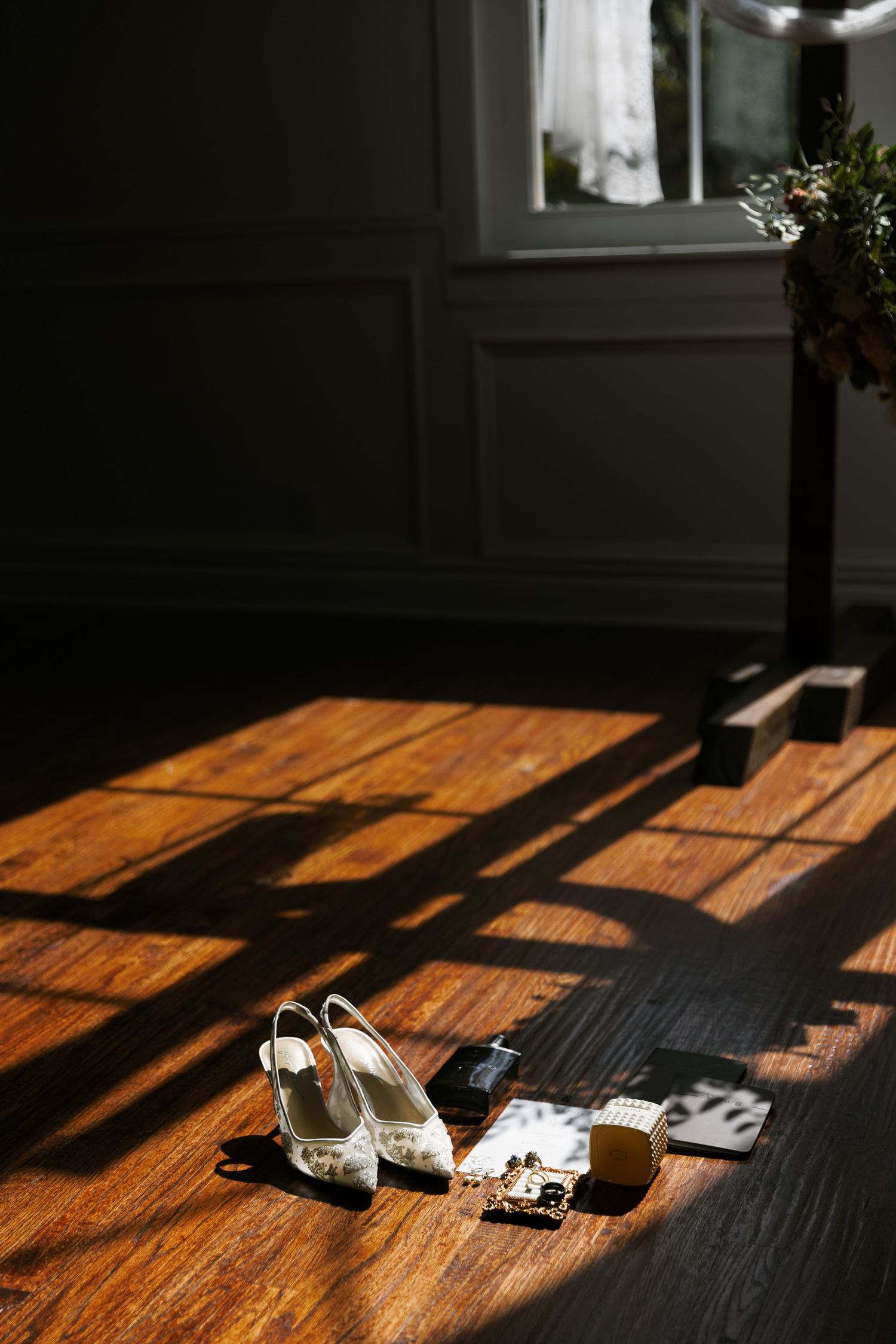 A sequence of sunlight and shadows cast on a wooden floor with white shoes and objects creating dramatic contrast.
