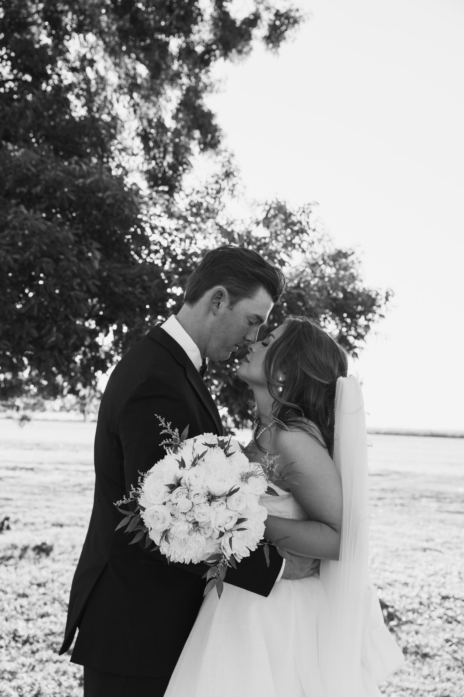 A romantic black and white wedding photo sequence shows a couple sharing a kiss while holding a white floral bouquet.