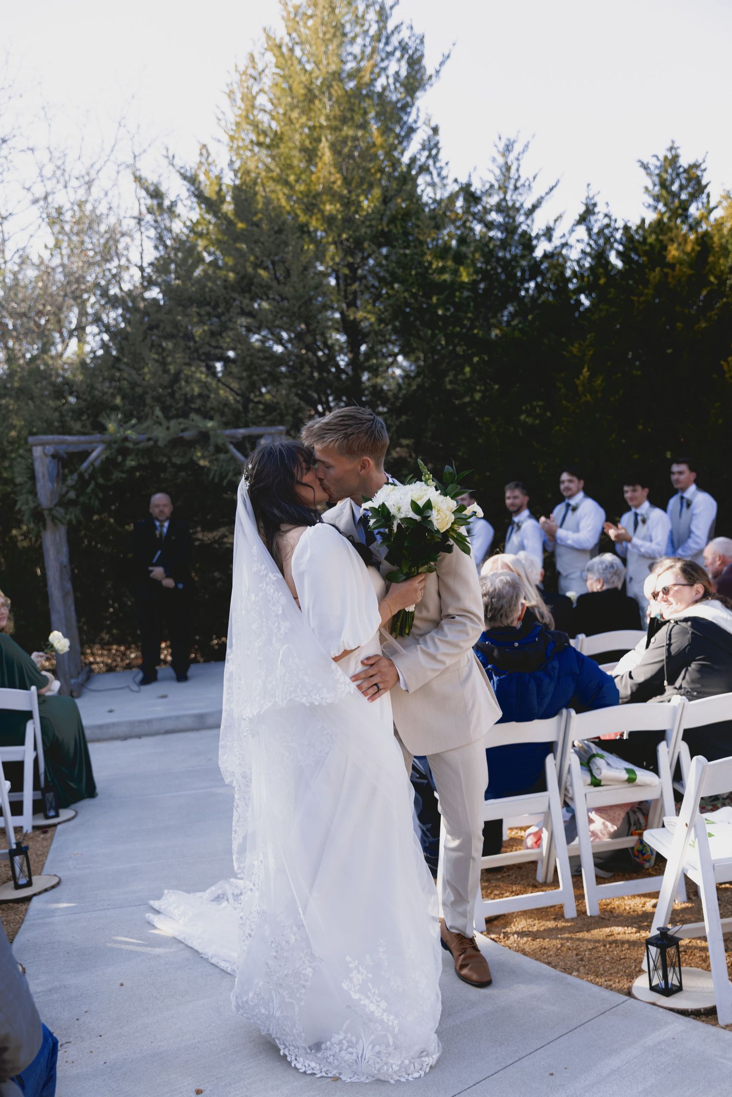 A romantic wedding ceremony moment captured in a series of photos showing a couple's first kiss at an outdoor venue.