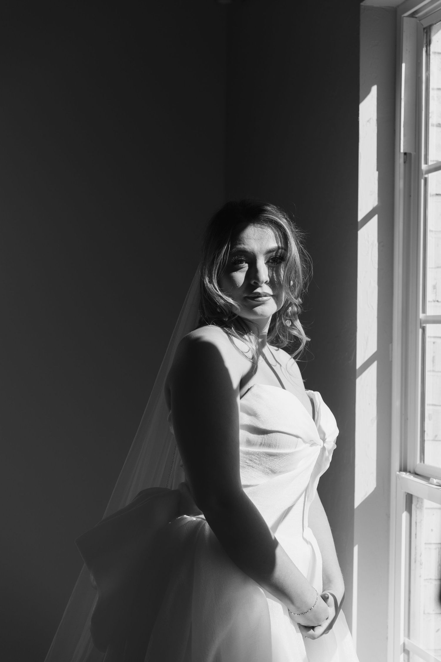 A dramatic black and white photo series showing a figure in white by a window with natural light casting shadows.