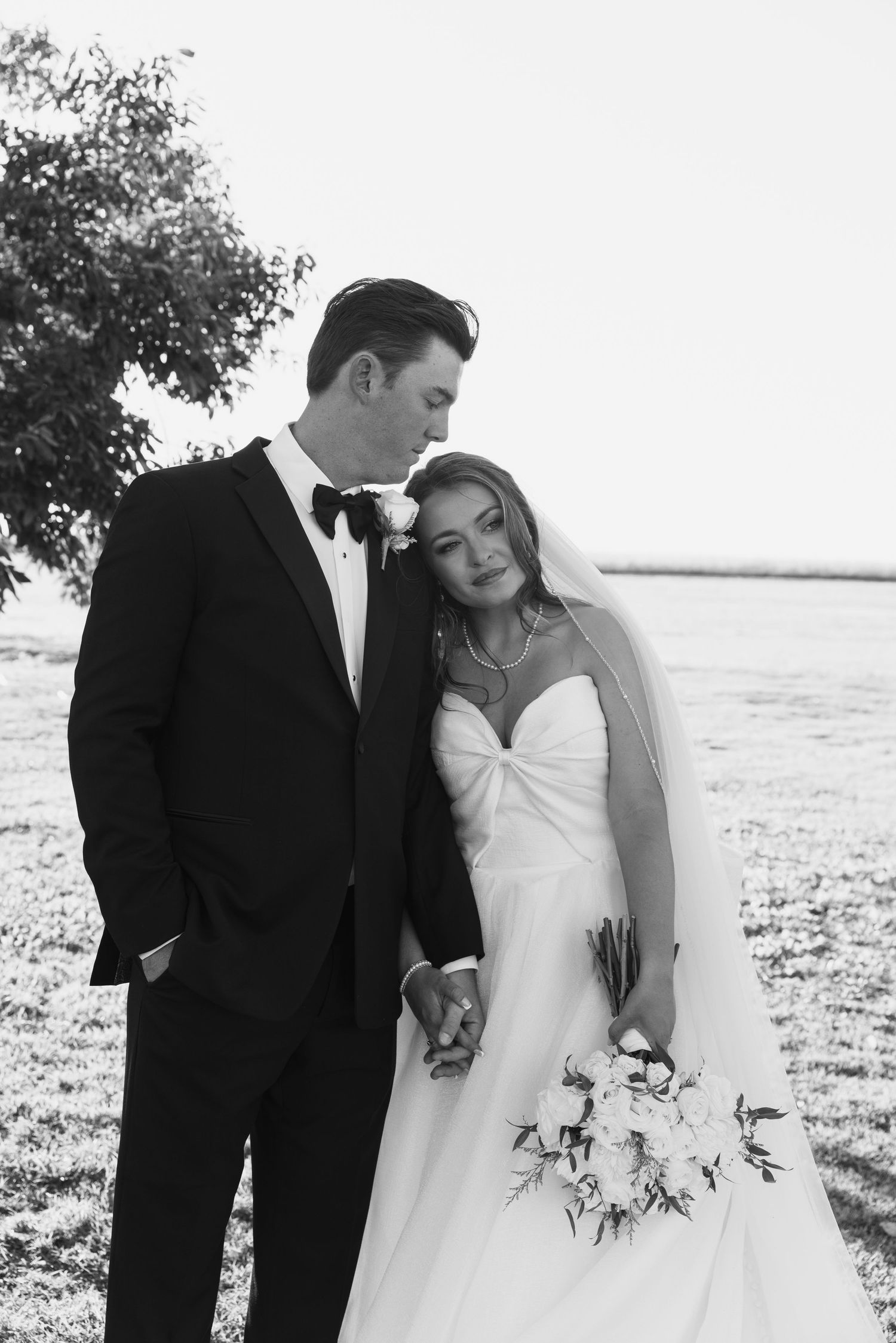 Black and white wedding photos show romantic moments between a couple on a bright beach setting.