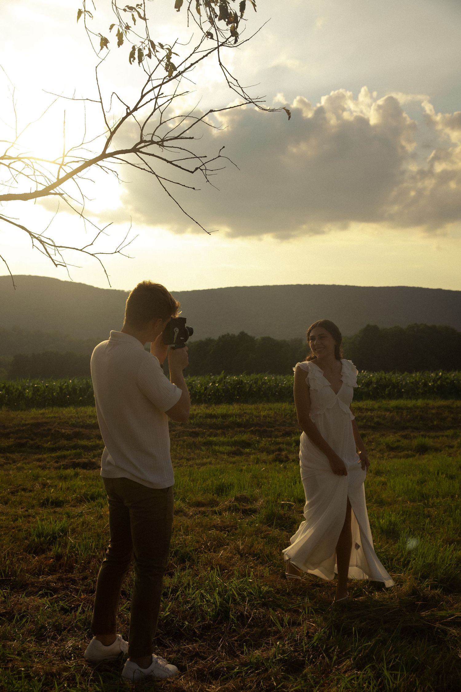 Two people photographing each other in a field during sunset.