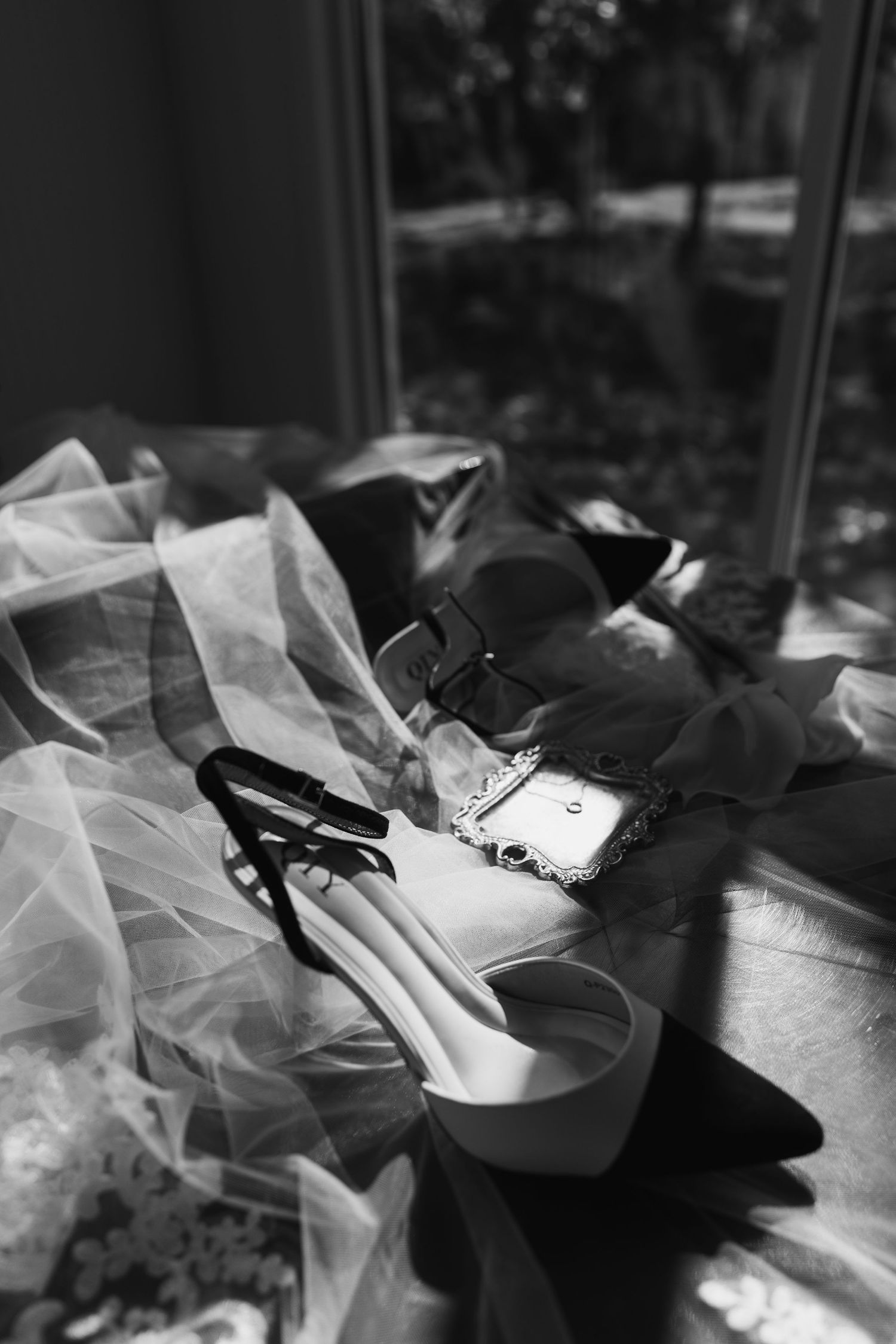 Black and white photograph of ballet shoes with tulle fabric creating an artistic composition in natural light.