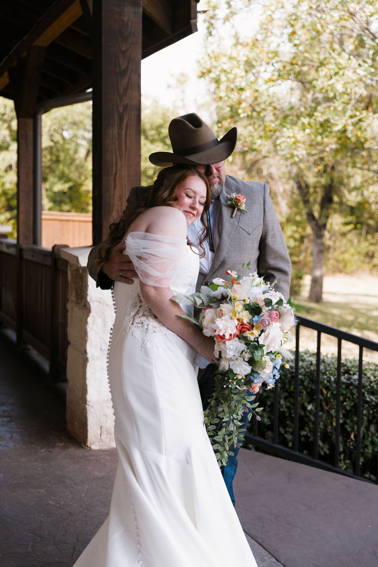 A romantic wedding couple shares tender moments in a rustic covered porch setting with floral bouquets.