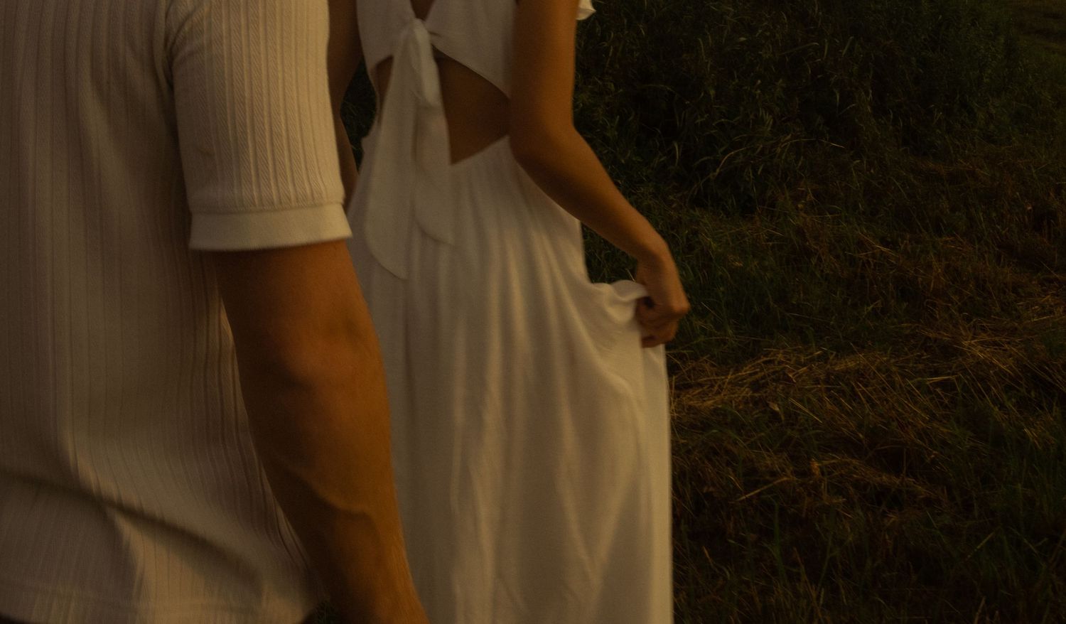 A tender moment captured between two people in white clothing at sunset.