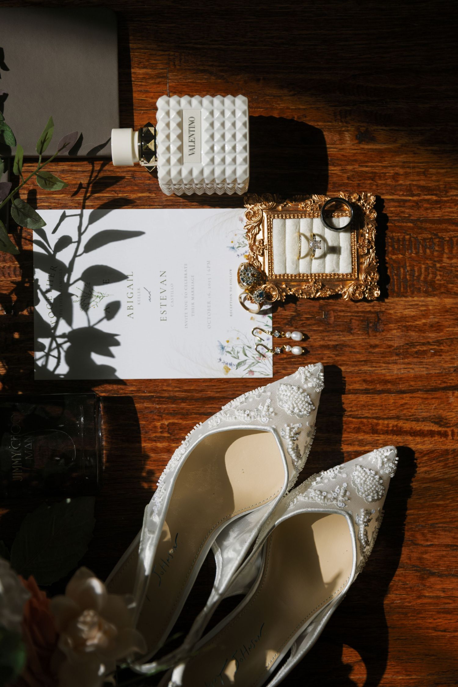 White lace wedding shoes and plant shadows on a rustic wooden surface with textural details and dramatic lighting.