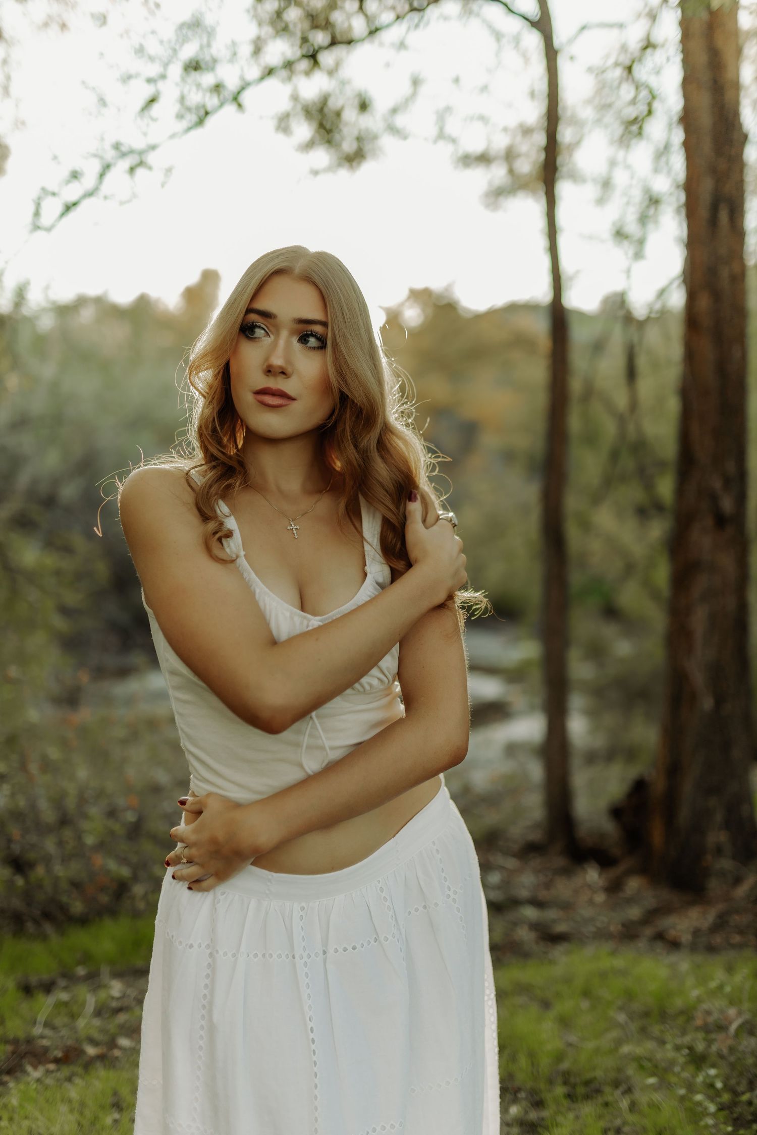 stunning senior photography of girl with arms crossed, posing in a field of trees during photoshoot in grand junction colorado