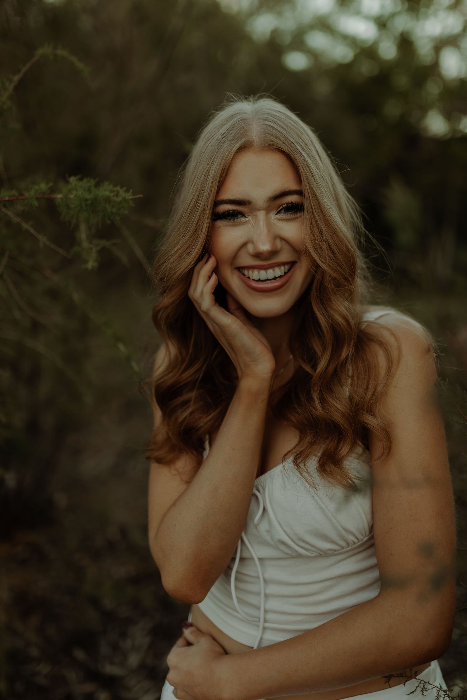 beautiful girl smiling during senior photoshoot in grand junction colorado, surrounded by leaves and bushes in scenic area
